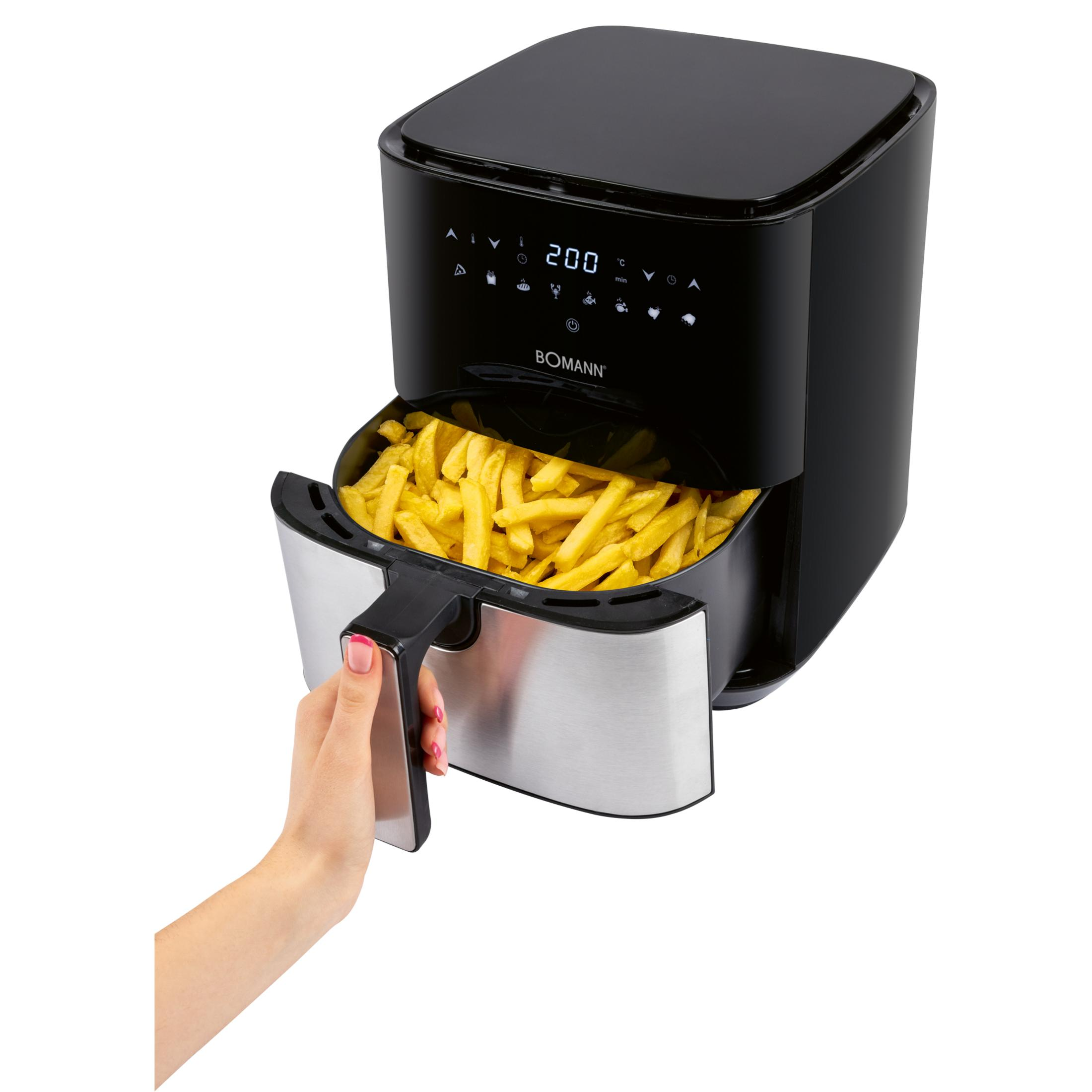 Ręka wyciąga szufladę pełną frytek z czarnej frytownicy beztłuszczowej.