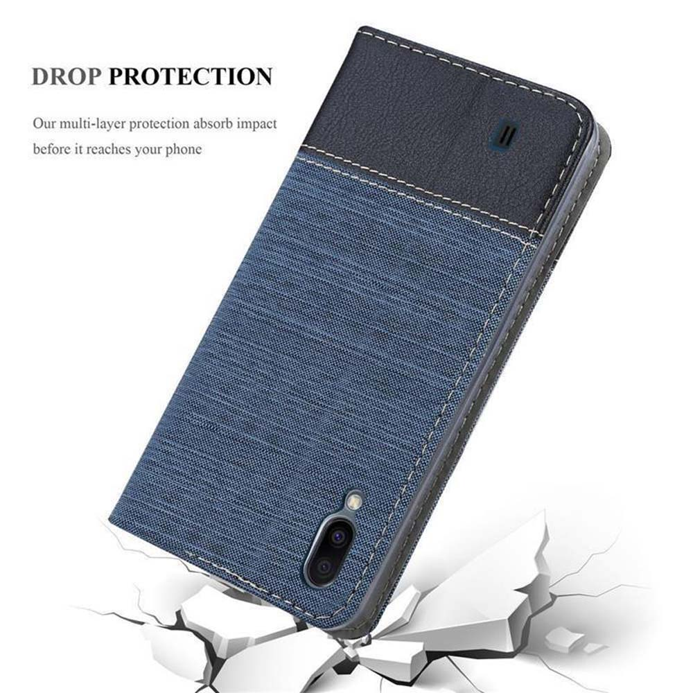 Custodia per telefono blu in tessuto e pelle con obiettivo della fotocamera che cade su blocchi bianchi rotti.