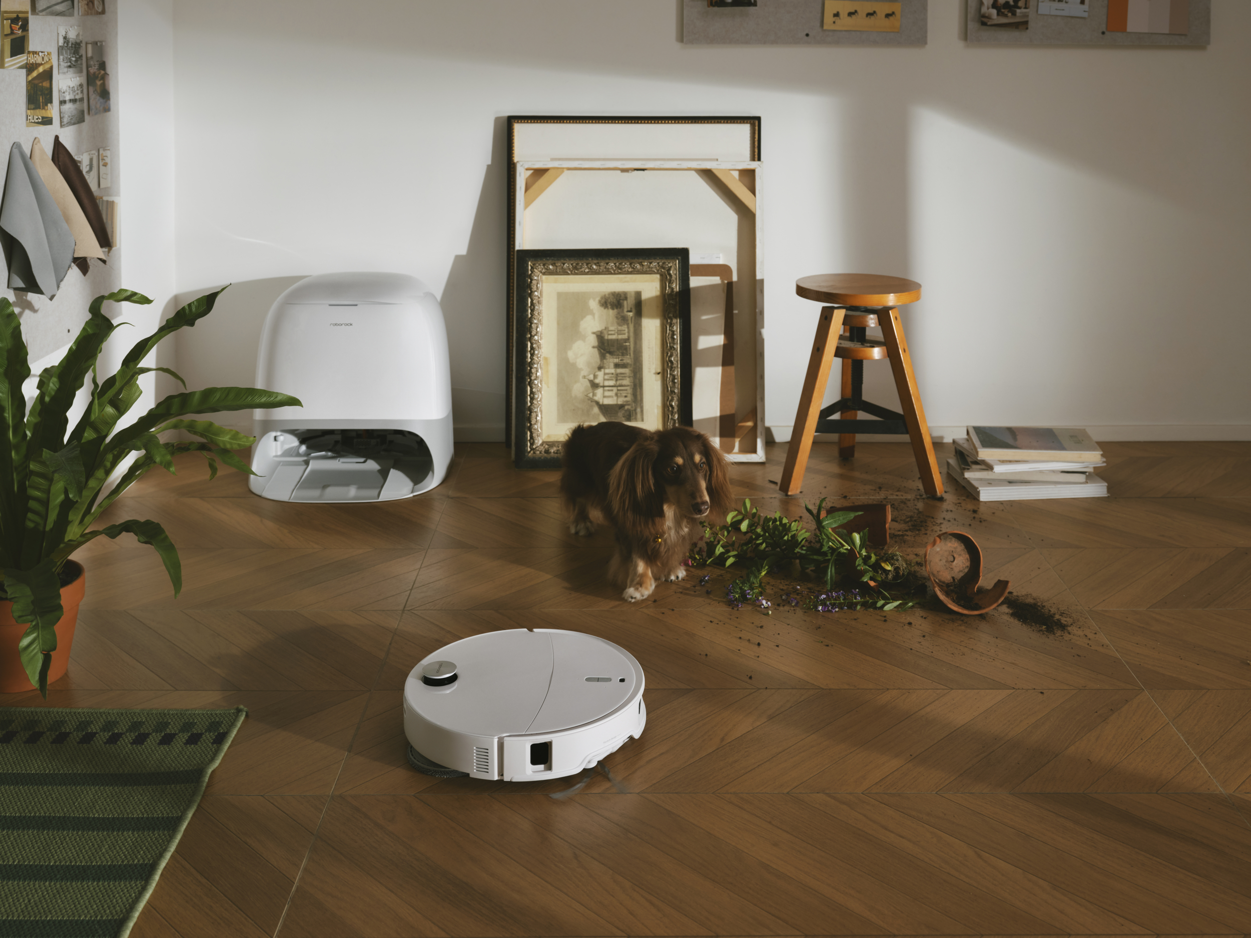 Un cane vicino a un vaso rovesciato e un robot aspirapolvere.