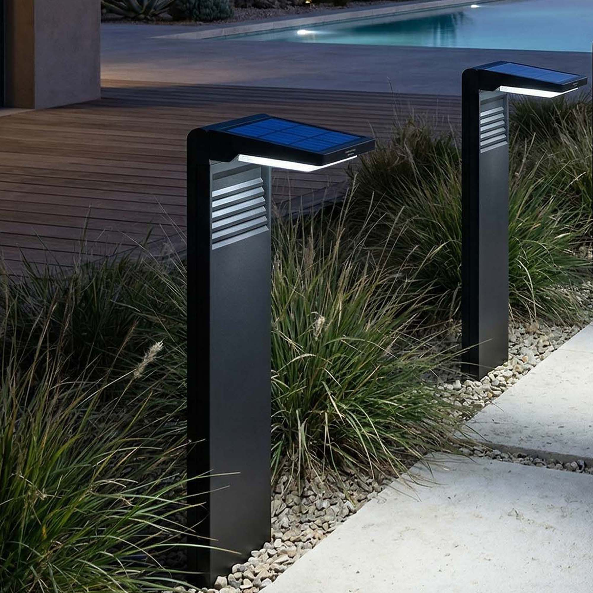 Moderne schwarze Solarleuchten säumen einen Weg neben einem Pool und einem Holzdeck.