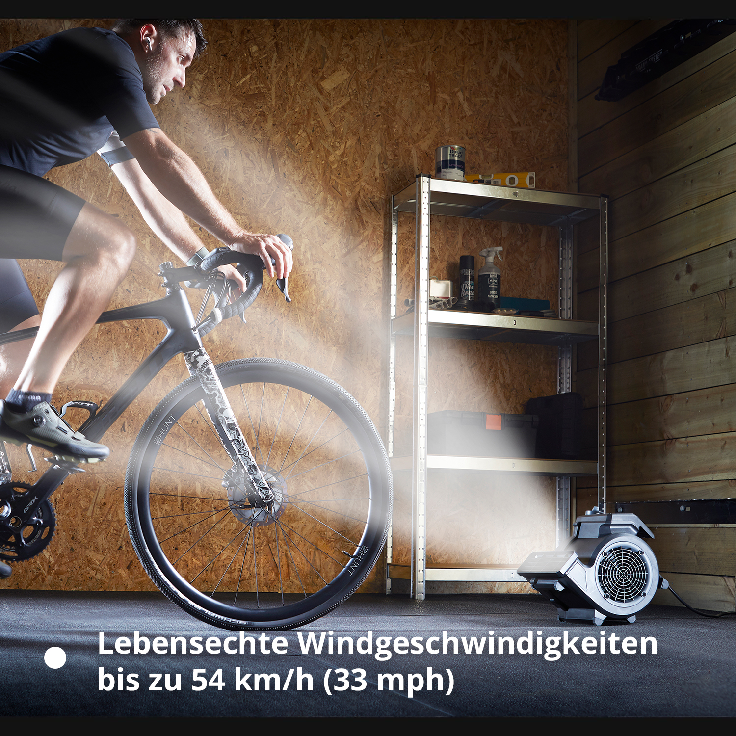 Mann fährt Rad auf Ergometer, Ventilator bläst Wind.