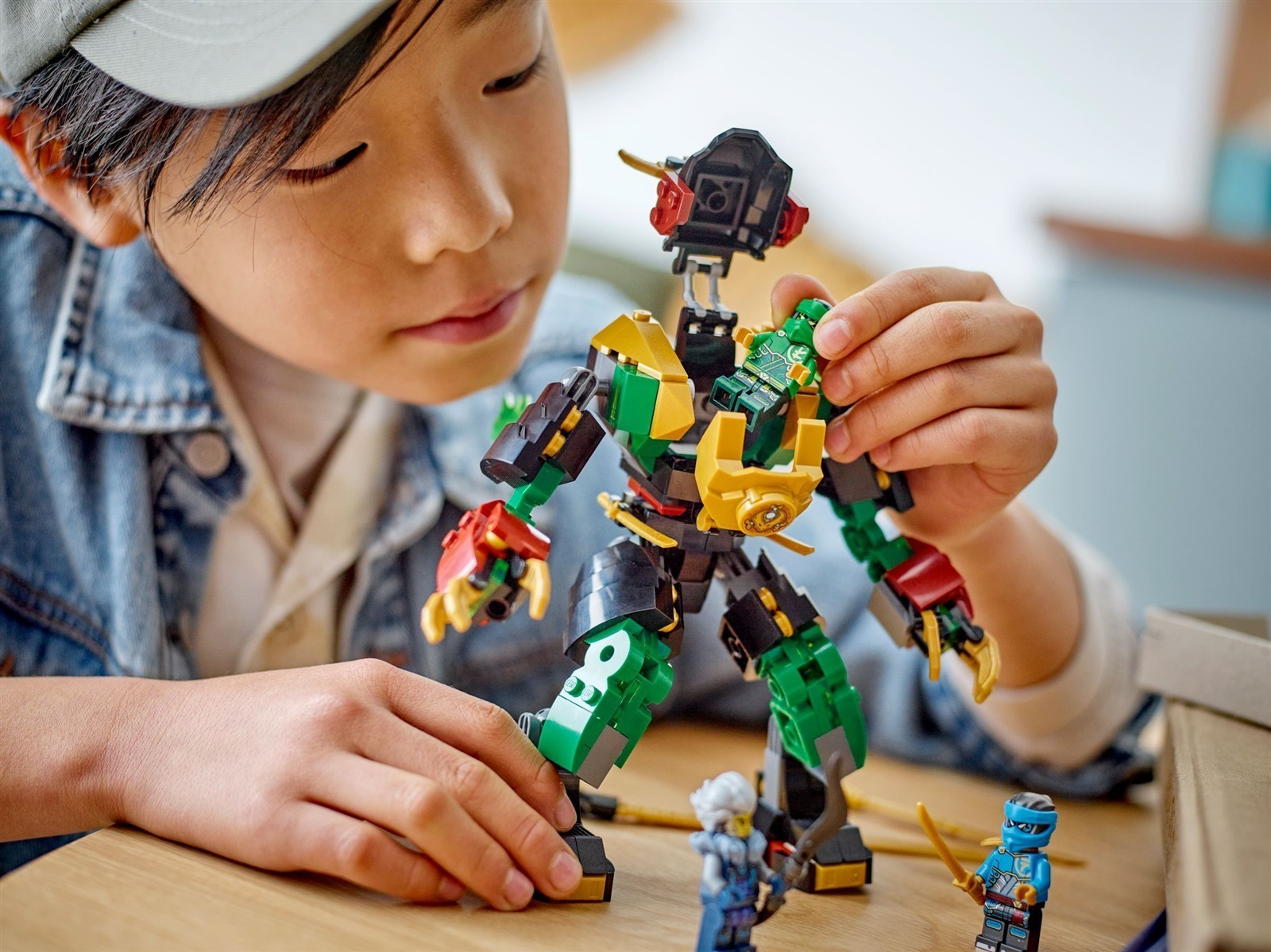 Ein Kind baut einen grünen und schwarzen Lego-Roboter und platziert eine kleine grüne Figur auf dessen Brust.