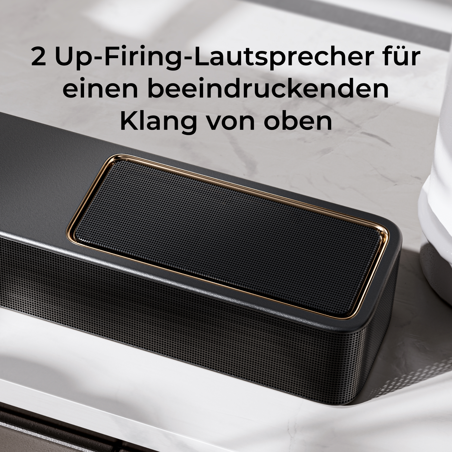 Black speaker with gold trim on a marble surface.