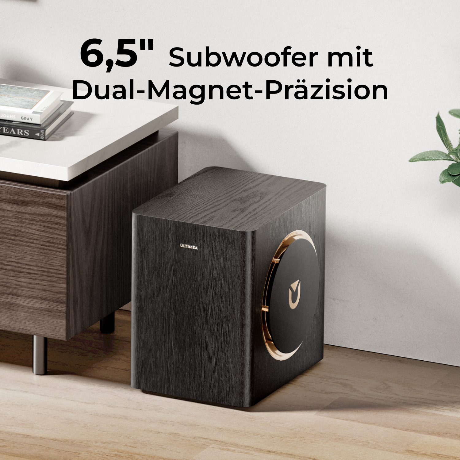 Czarny subwoofer z drewnianym ziarnem, złotym wykończeniem i logo, na podłodze.