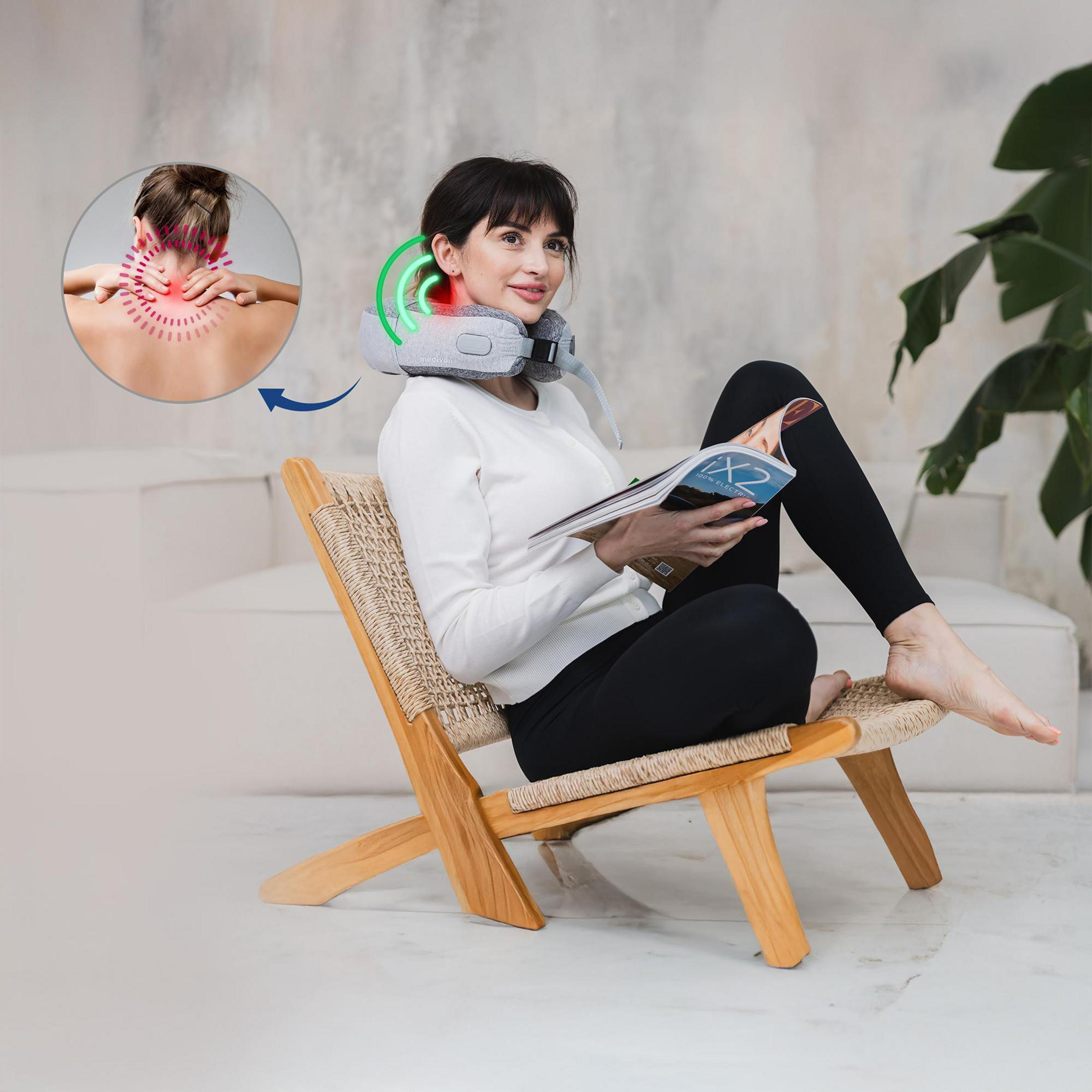 Frau mit Nackenmassagegerät liest im Stuhl.