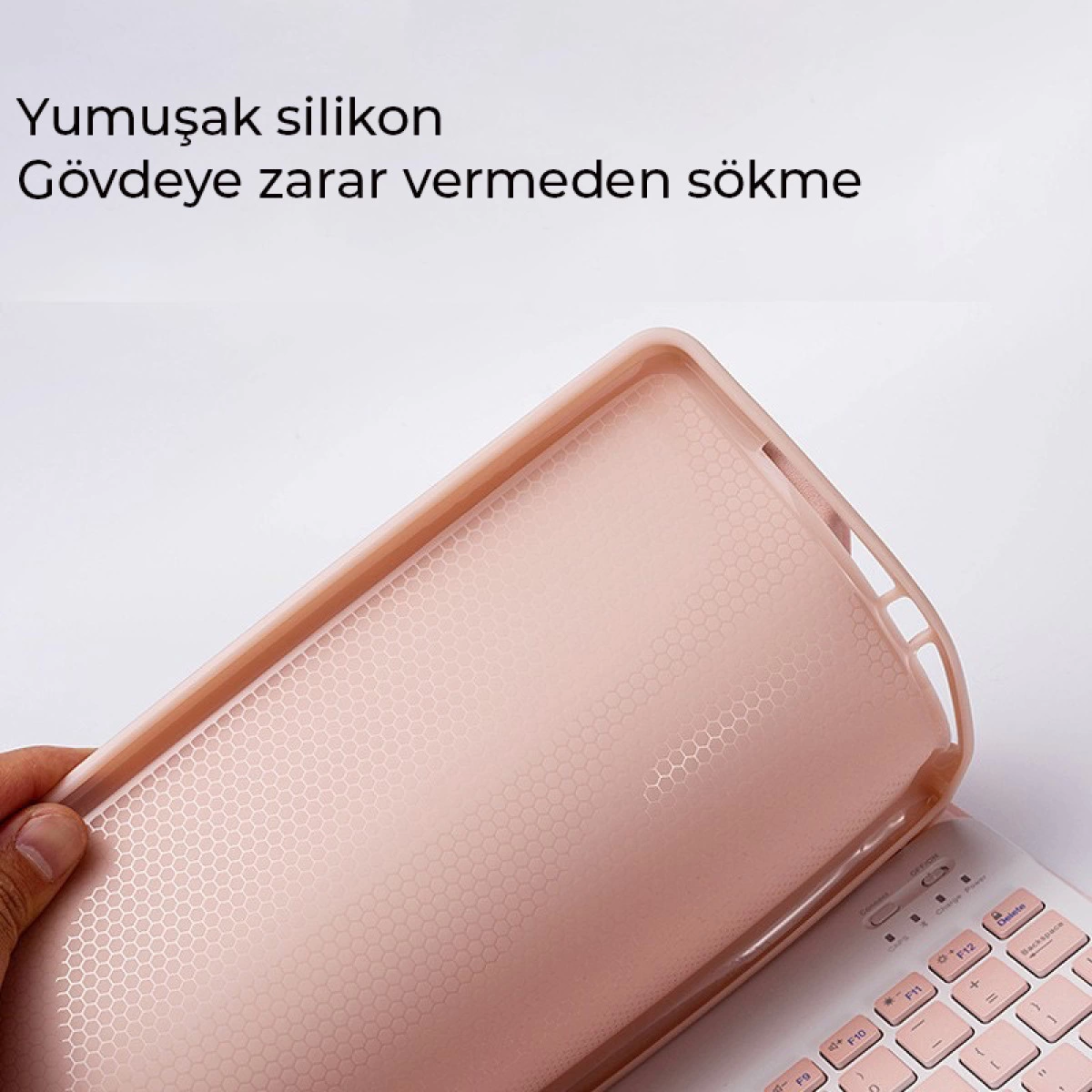 Pembe silikon kılıf bir klavyeden çıkarılıyor. Kılıfın petek deseni var.
