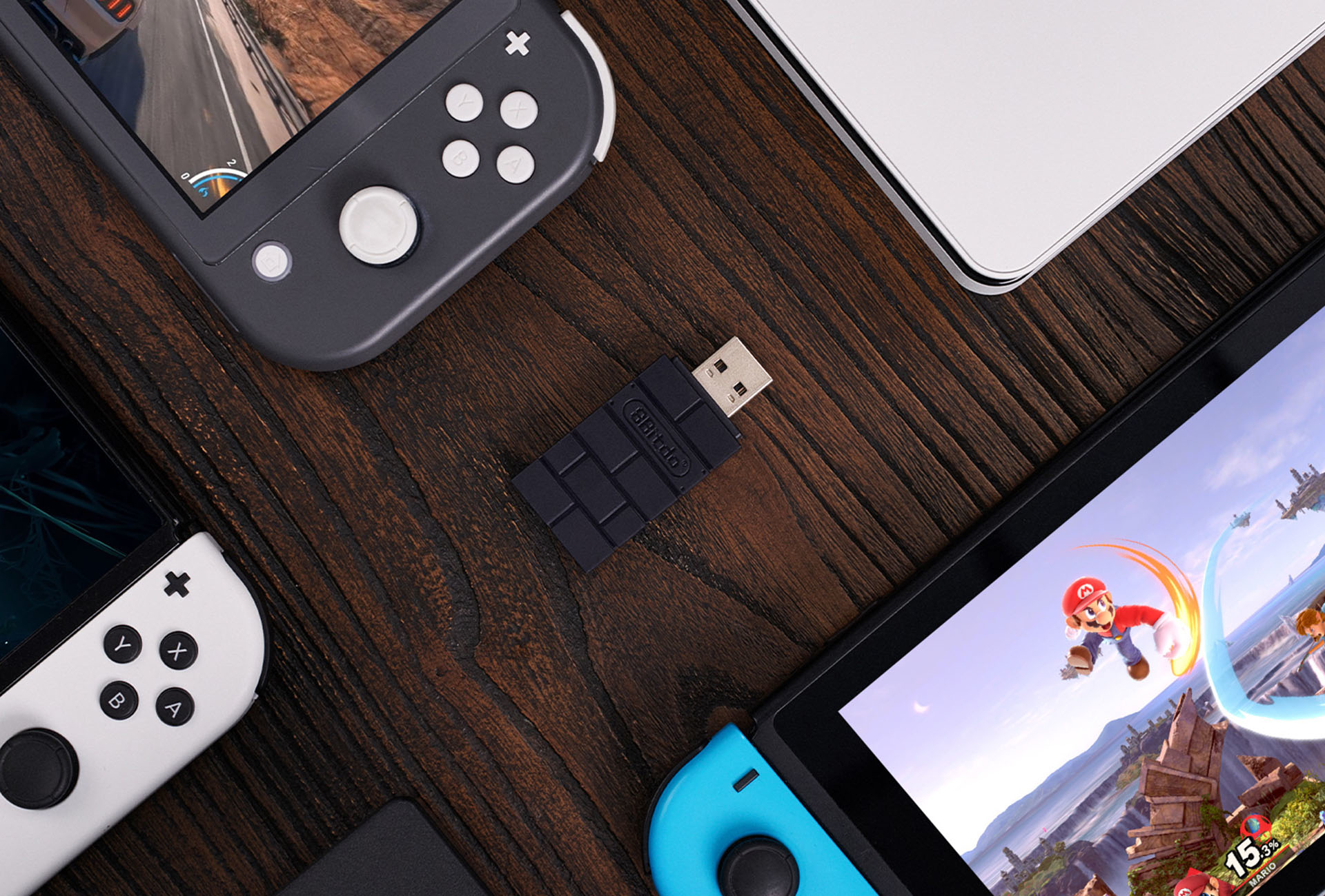 Console Nintendo Switch, un adattatore USB e un laptop su un tavolo di legno.