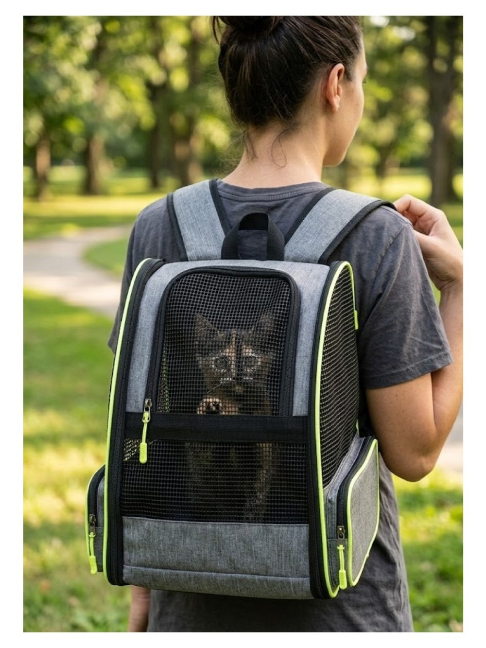 Bir kadın parkta içinde yavru kedi olan bir sırt çantası taşıyor.