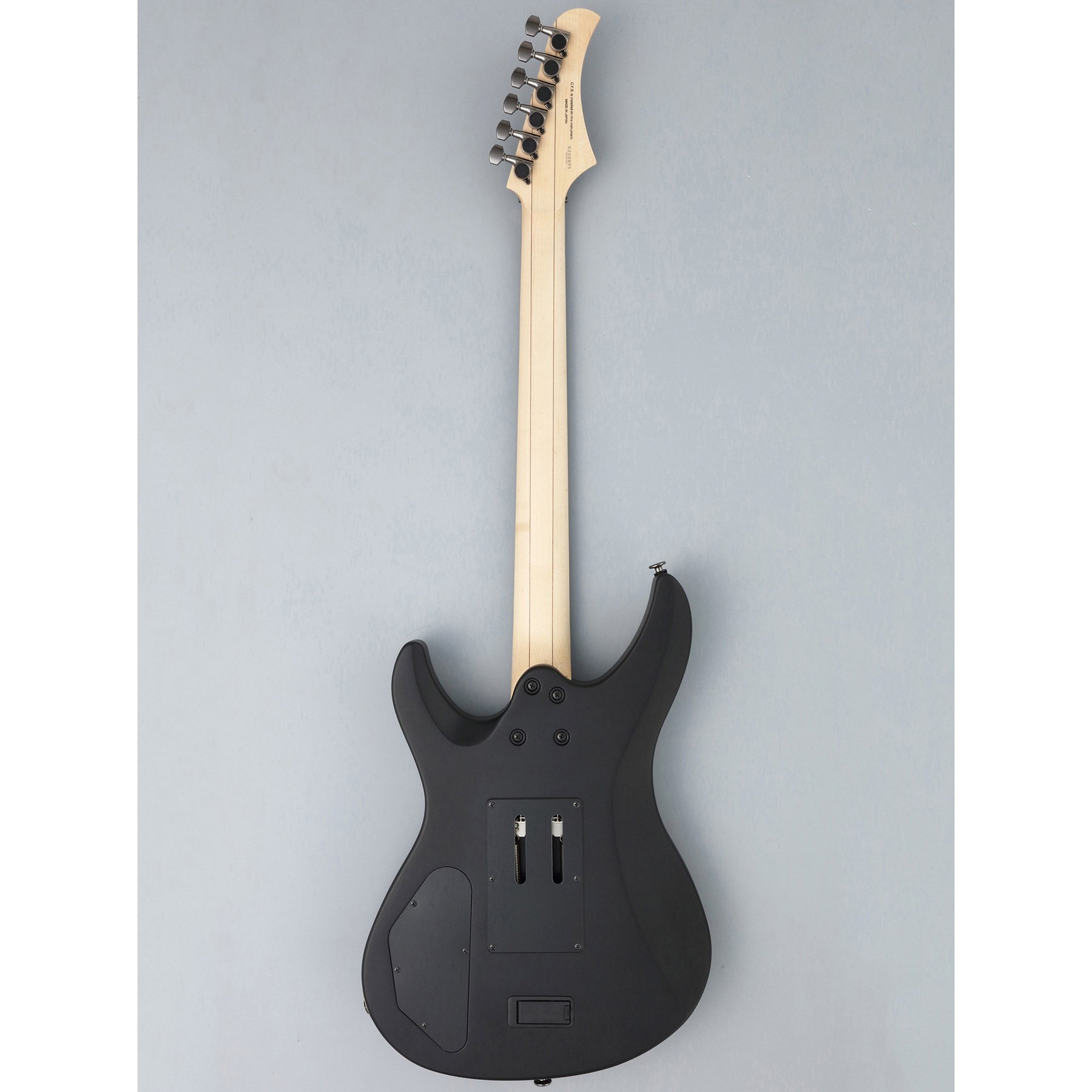 Açık ahşap klavyeli ve gümüş burgulu siyah elektro gitarın arkadan görünümü.