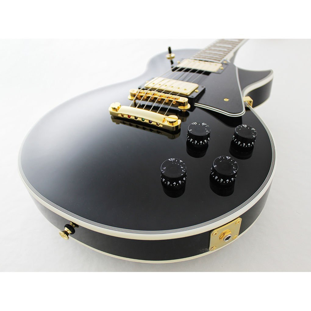 Altın donanımlı ve dört siyah kontrol düğmeli siyah elektro gitar.
