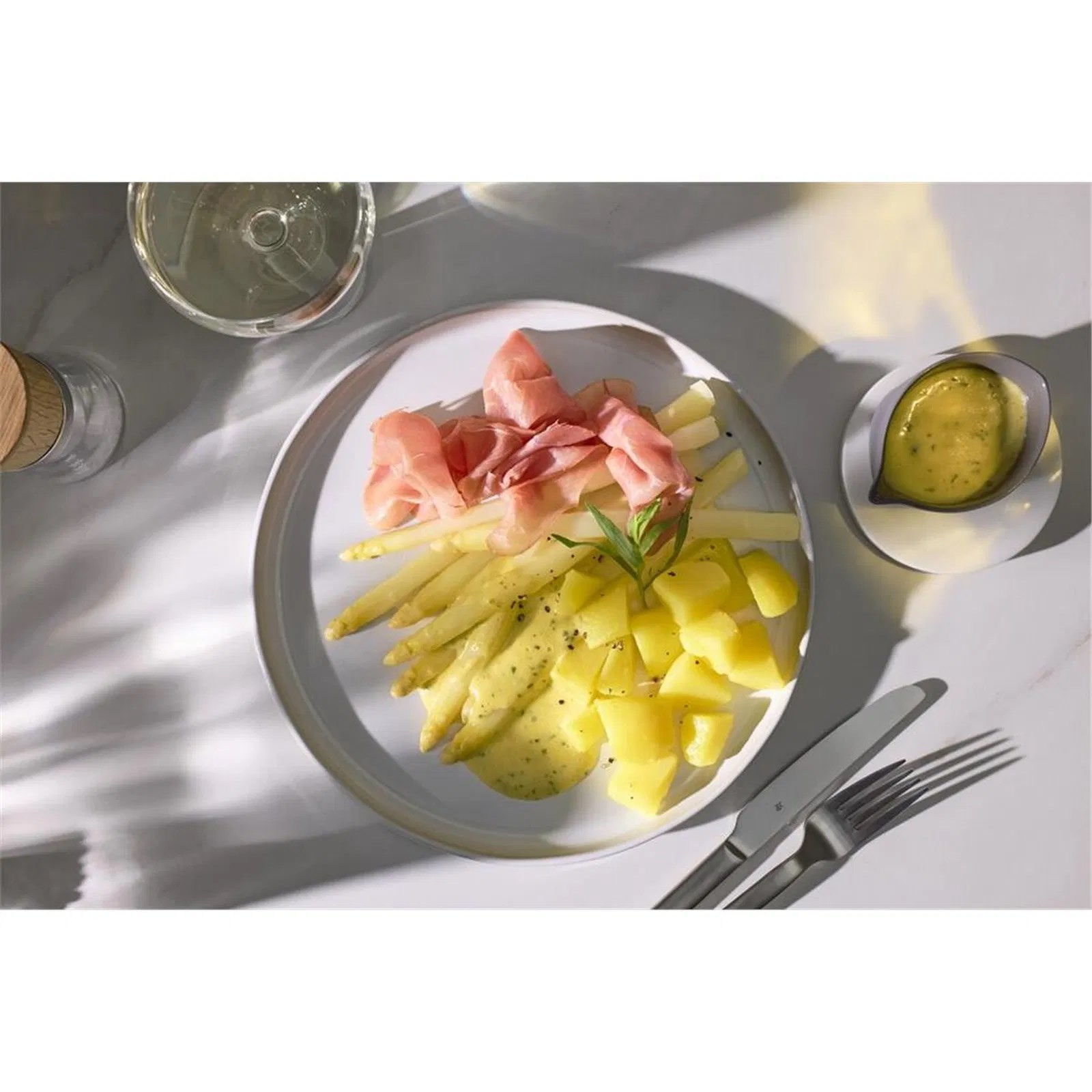 Sos ve bir kadeh şarap ile tabakta kuşkonmaz, jambon ve patates.
