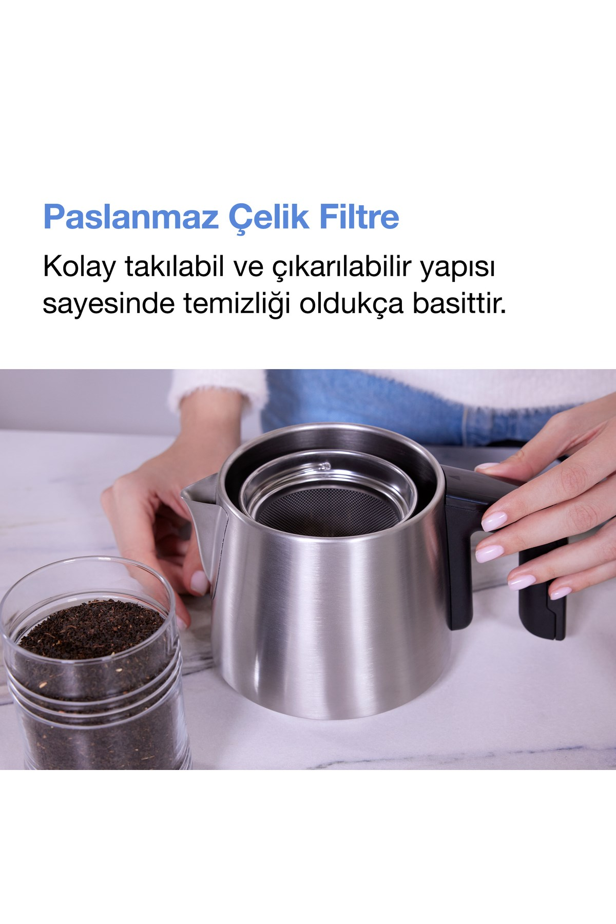 Bir kişi, dökme çay bardağının yanında paslanmaz çelik çaydanlık tutuyor.
