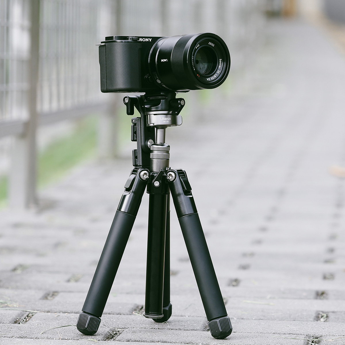 Czarny aparat Sony na statywie stoi na utwardzonej ścieżce.