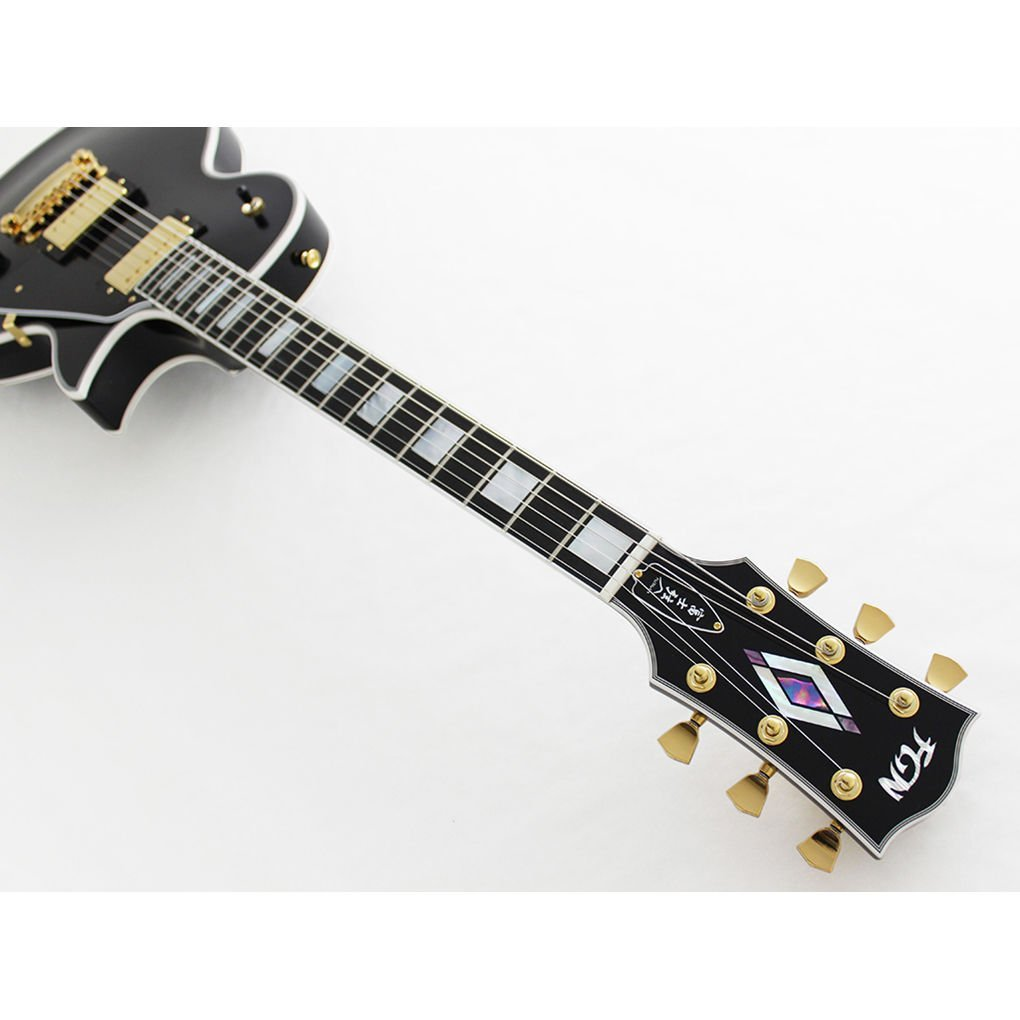 Beyaz arka plan üzerinde altın donanım detaylı siyah elektro gitar.