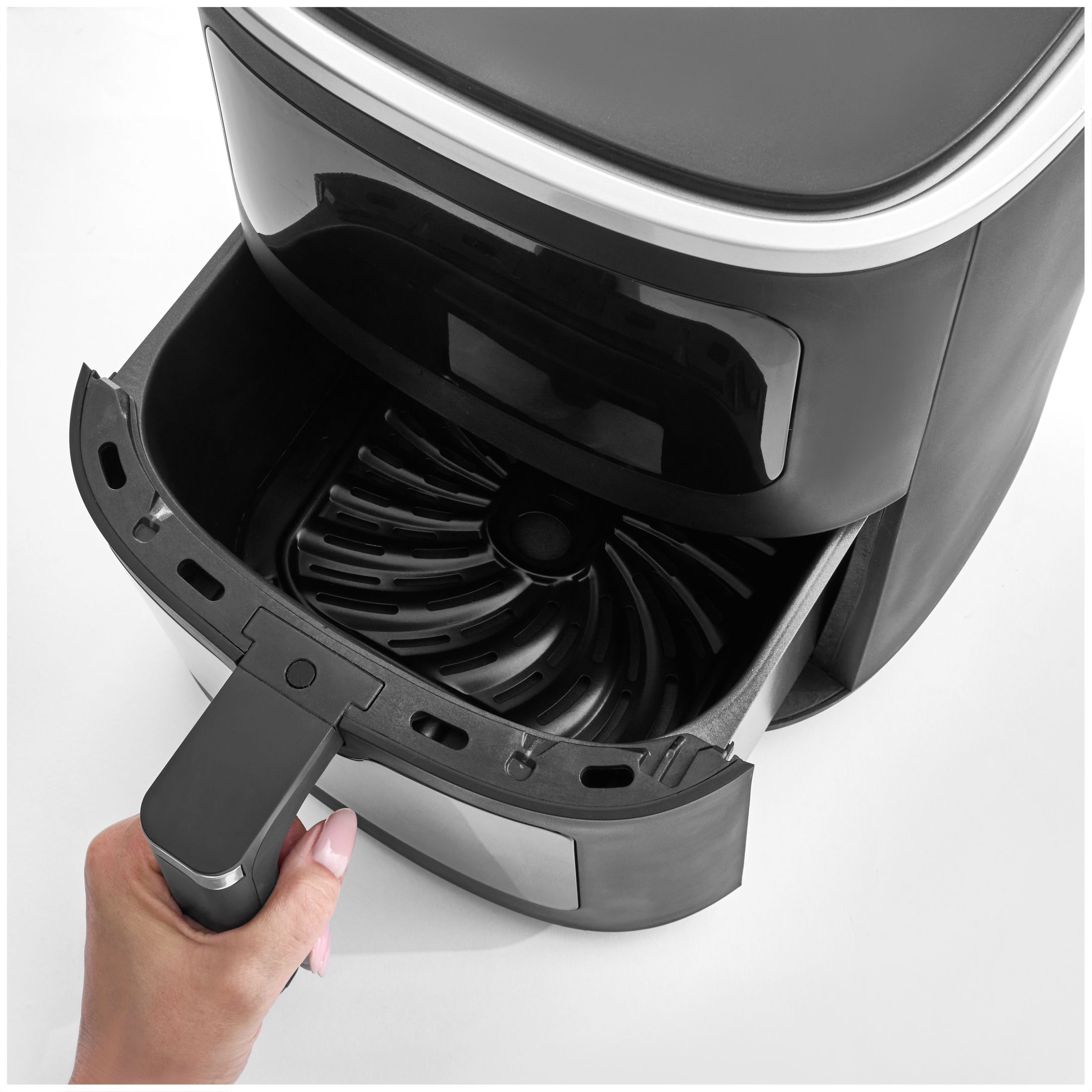 A hand pulls out the basket of a black air fryer.