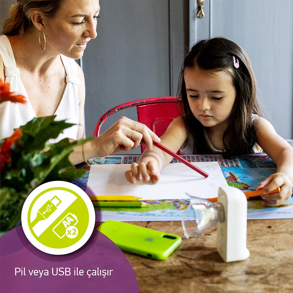 Kadın çocuğun çizmesine yardım ediyor. Masada kalemler, telefon, kalemtıraş. Pil/USB simgesi.