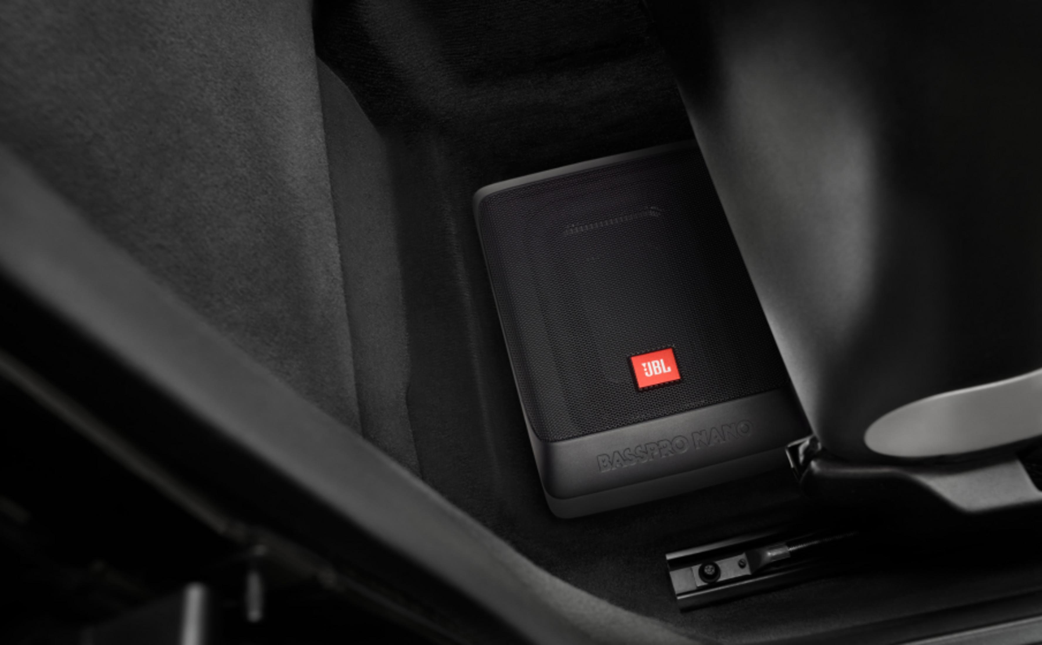 Caisson de basses JBL Basspro Nano noir sous un siège auto.