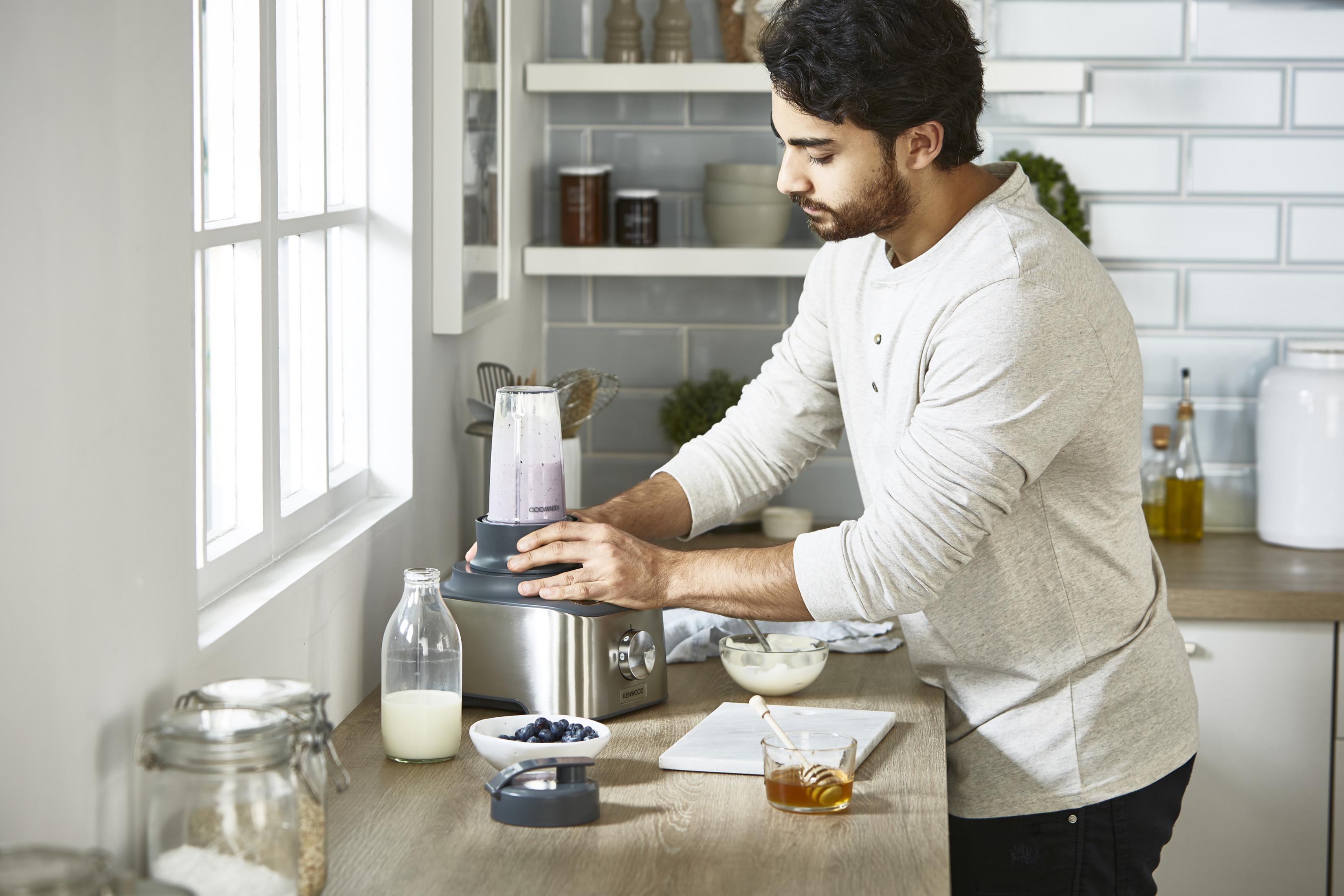 Mężczyzna robi smoothie w blenderze w kuchni.