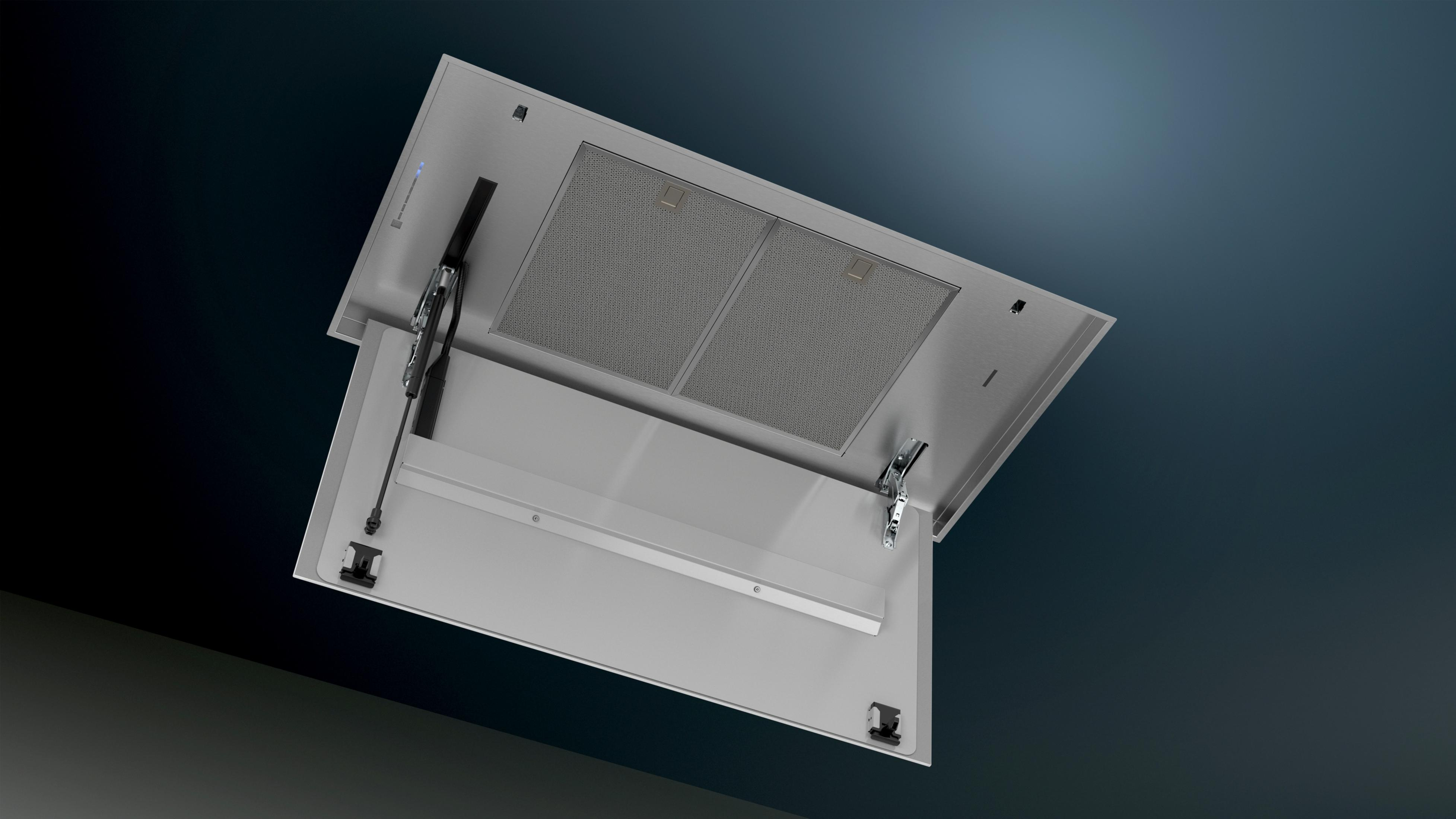 An open metal range hood showing filters and hinges against a dark background.