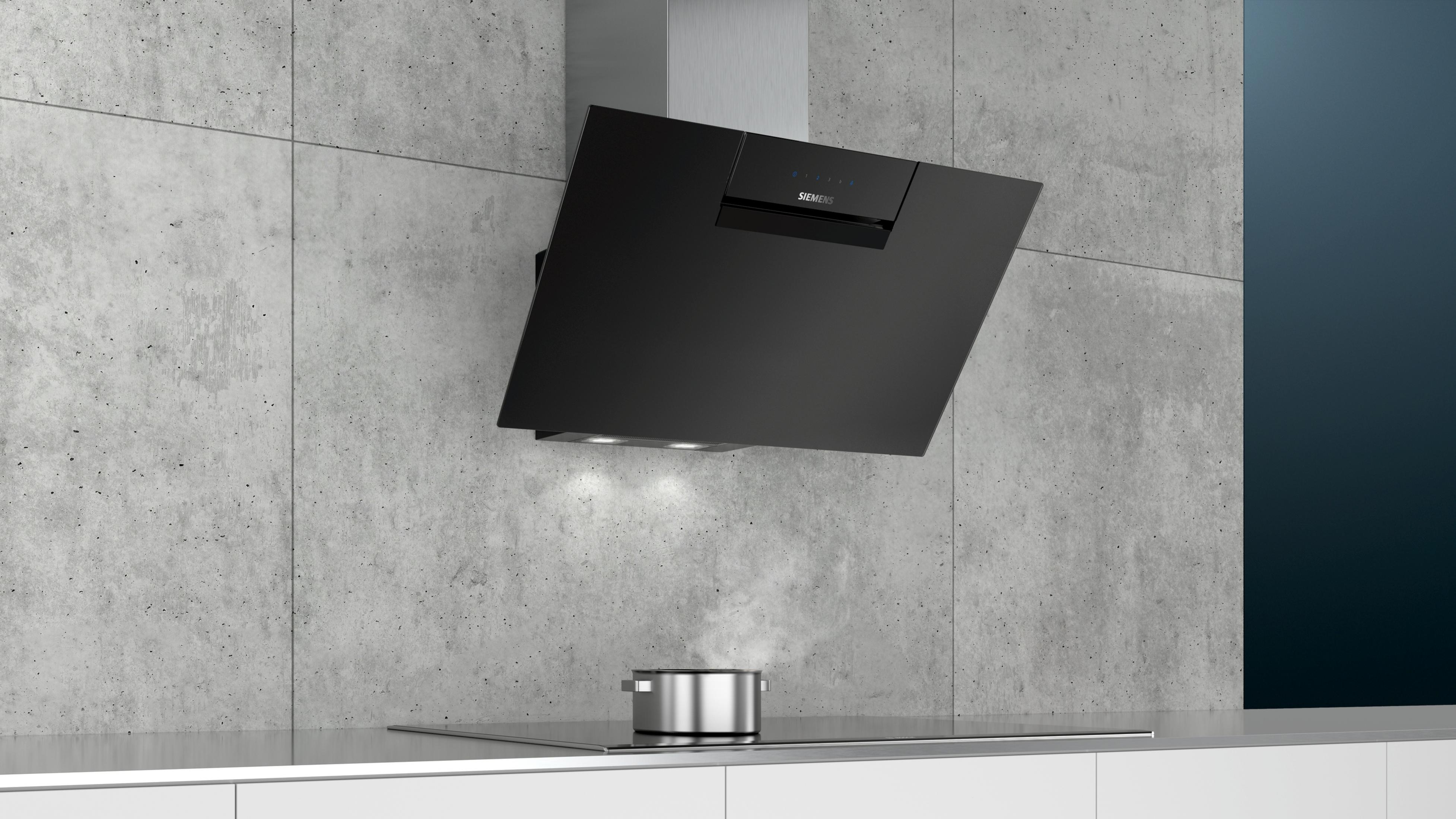 Black range hood over stovetop with pot, steam rising.