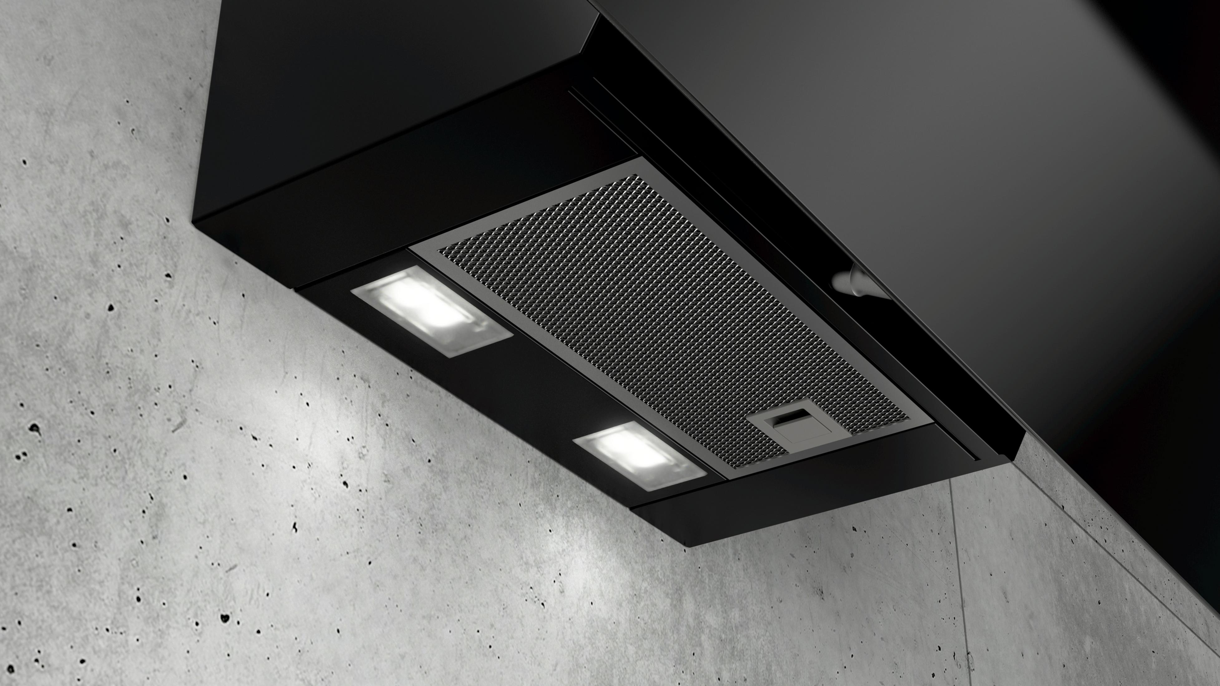 Black range hood with lights above a concrete wall.