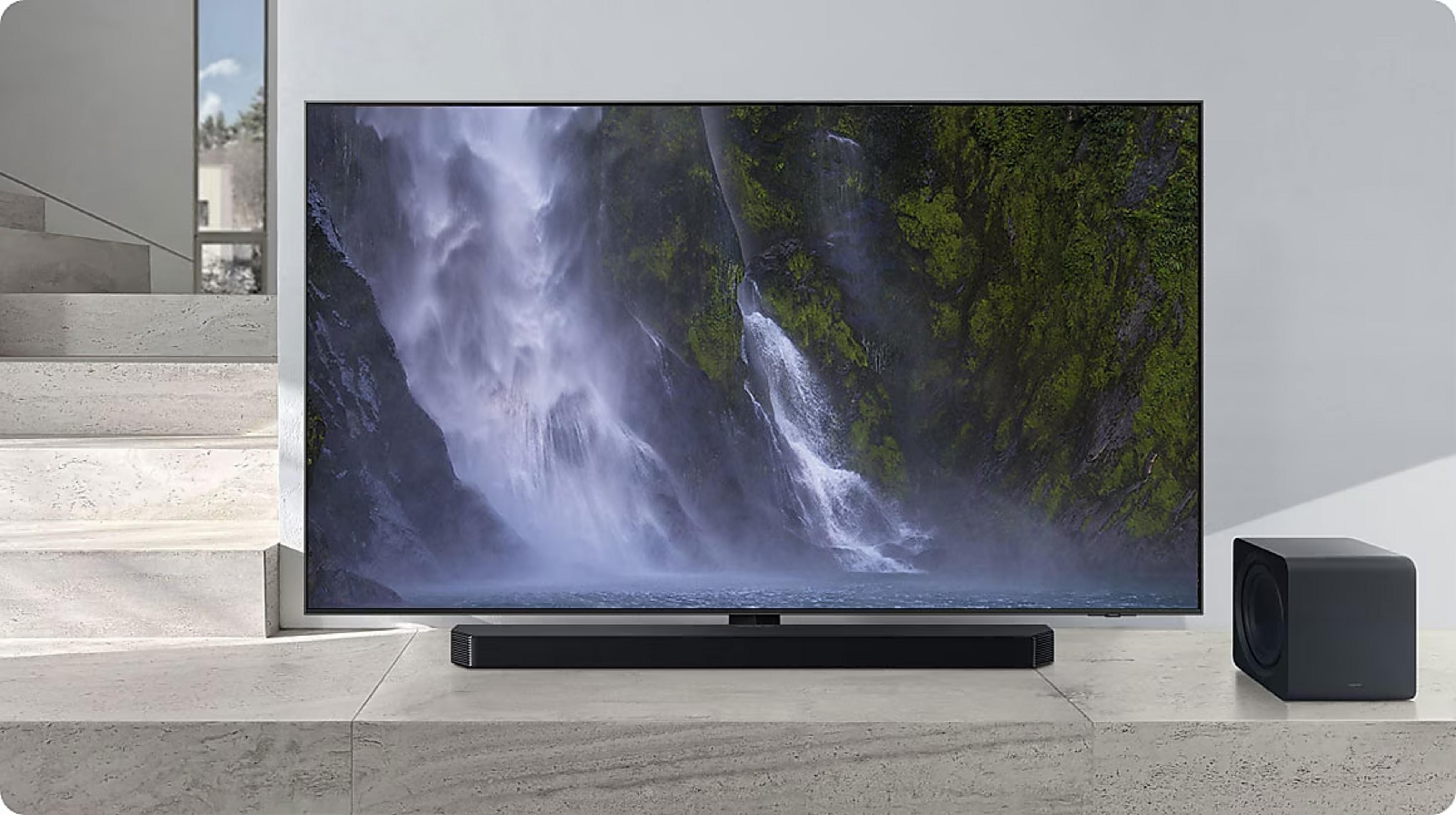 A modern TV displays a waterfall. A soundbar and subwoofer sit beside it.