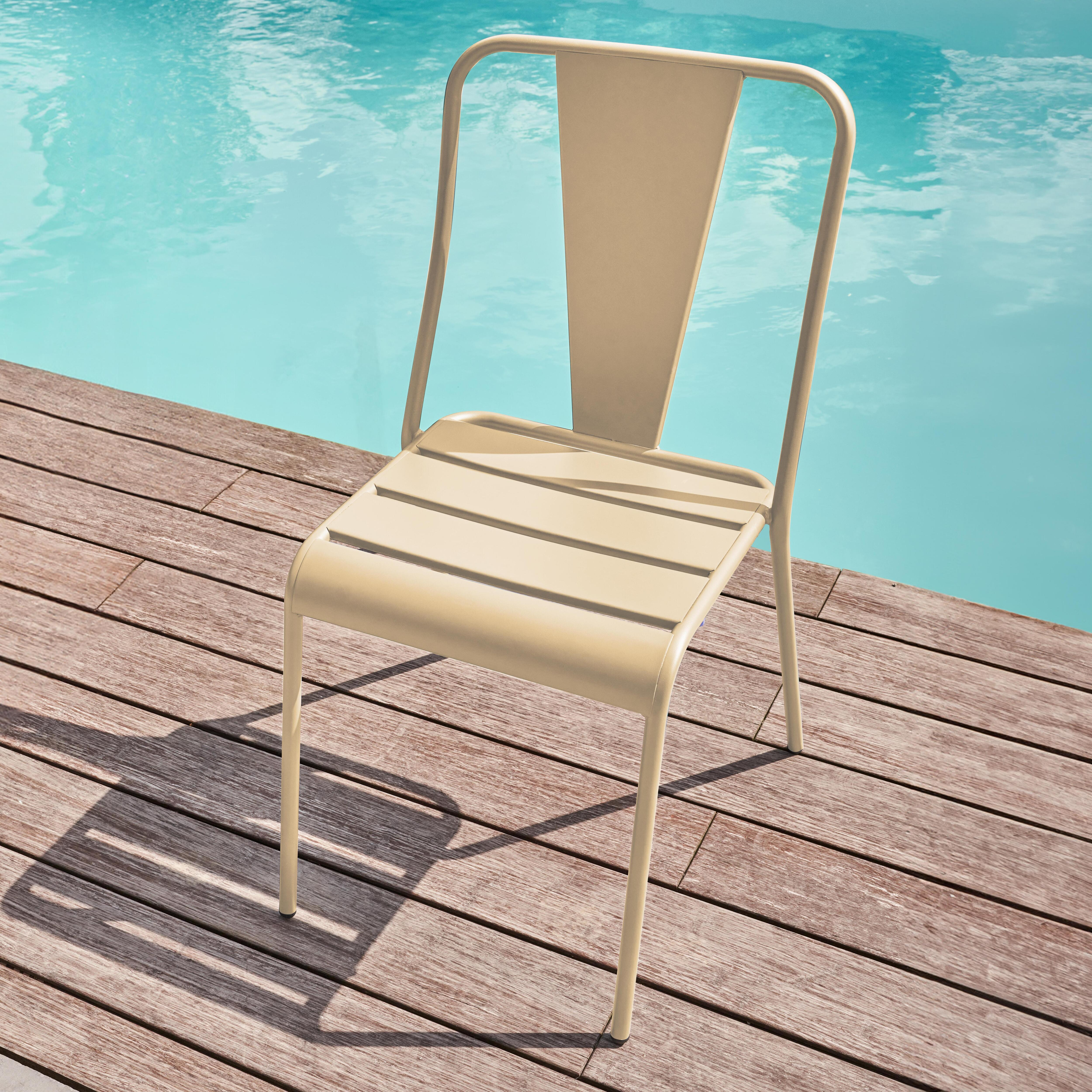 Ein beiger Metallstuhl steht auf einer Holzterrasse neben einem Pool.