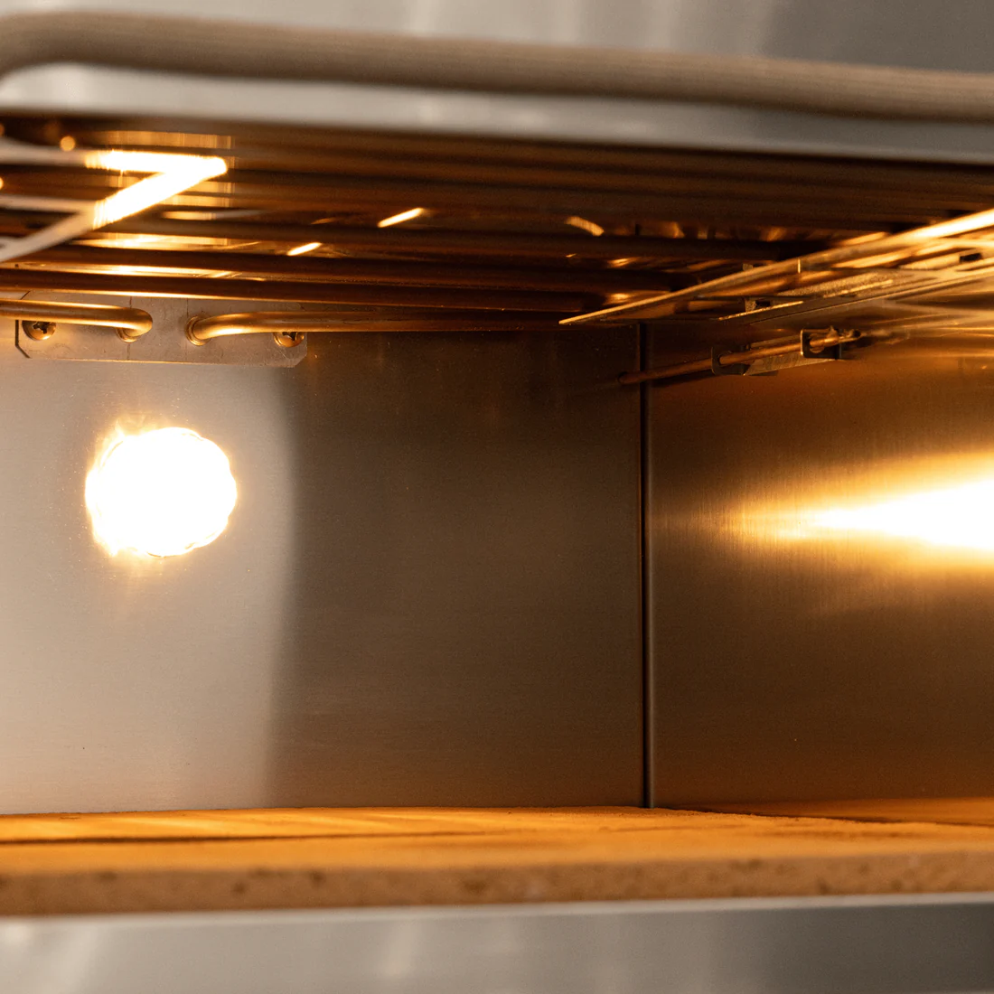 Vista interna di un forno con elementi riscaldanti e una luce.