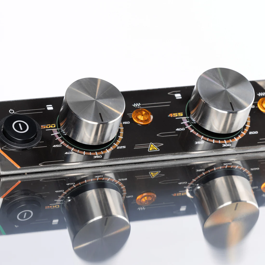 Un pannello di controllo nero con due manopole metalliche, display di temperatura e spie luminose.