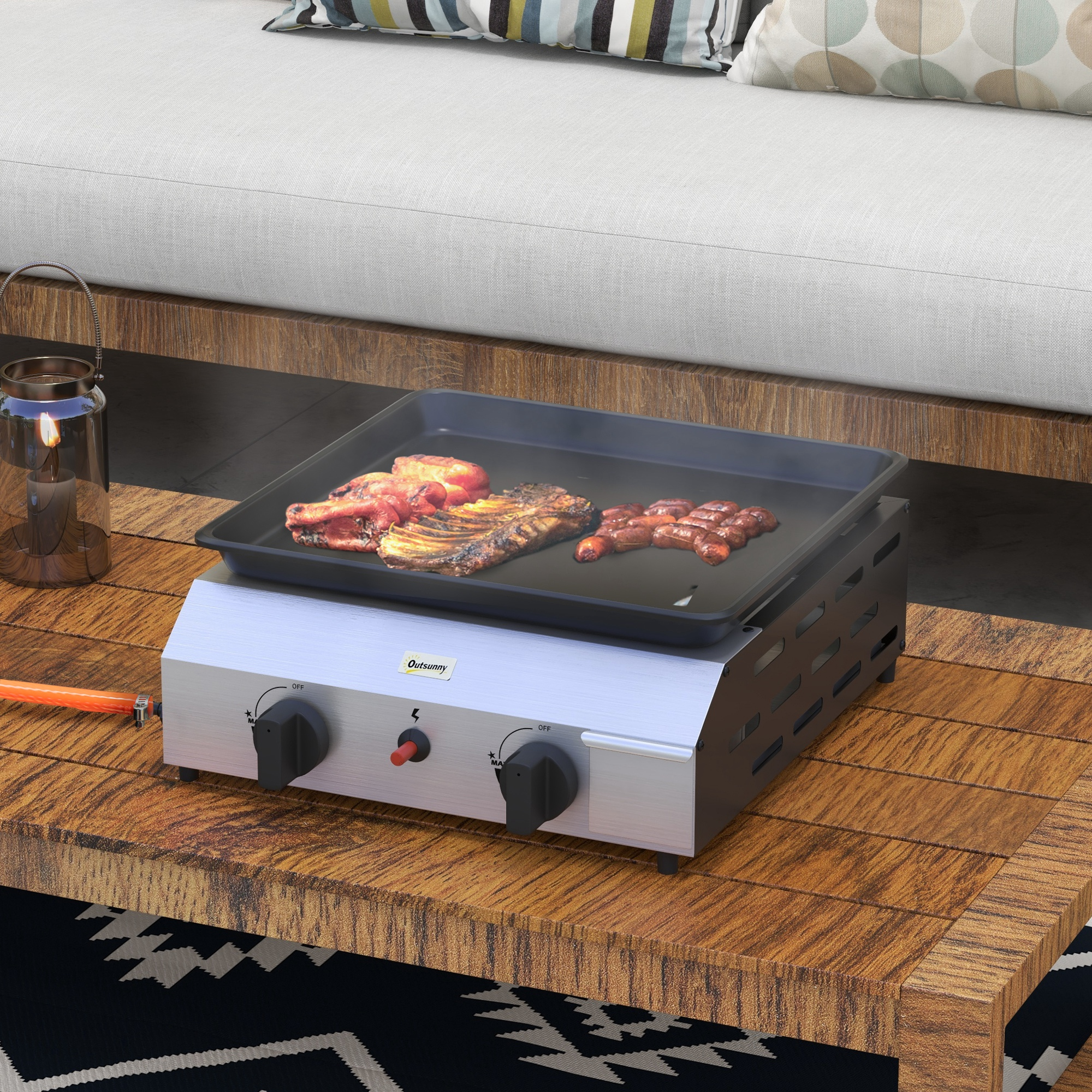 Una griglia a gas con carne e salsicce su una superficie di legno accanto a una candela.
