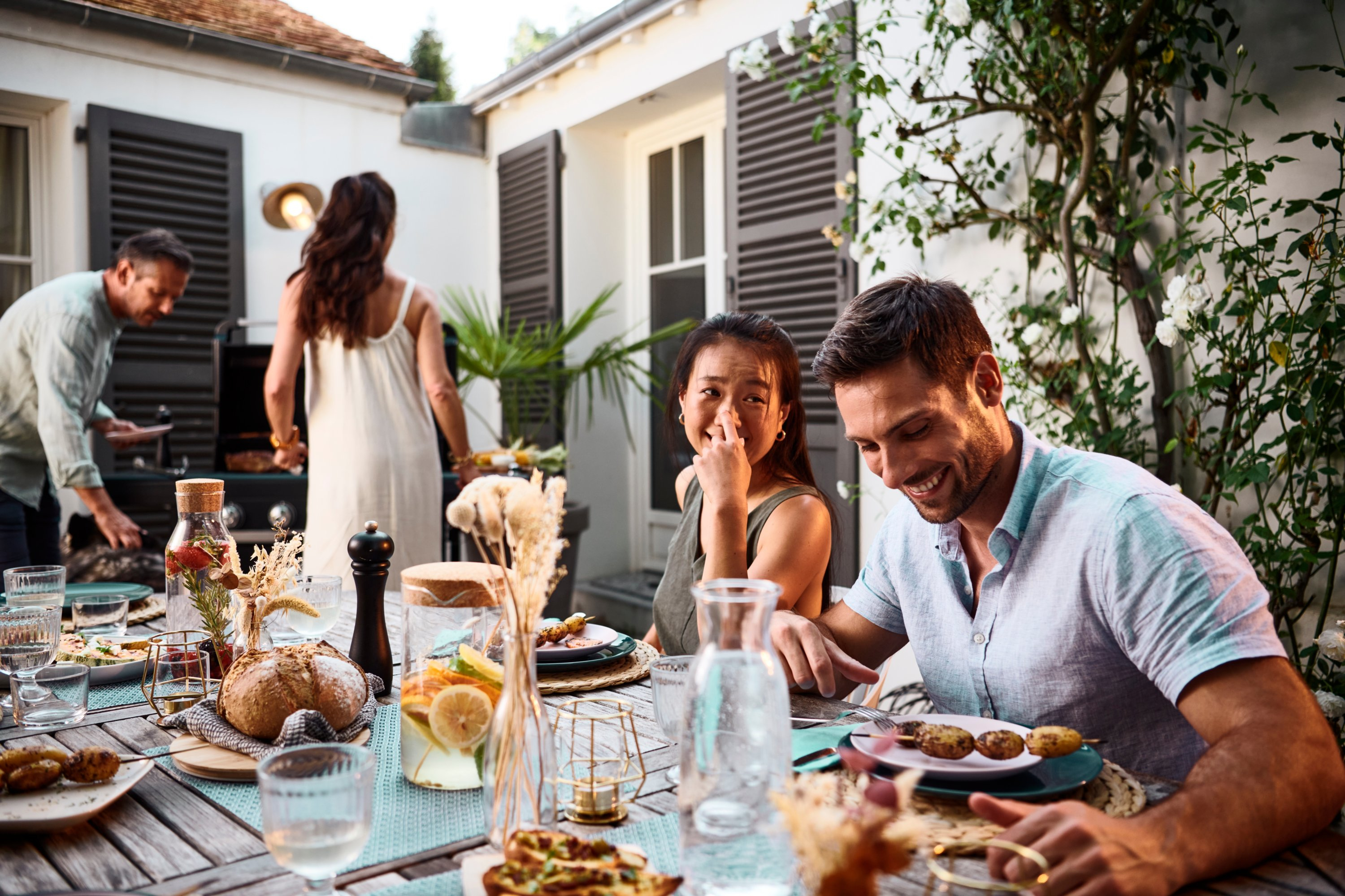 Amici si godono un barbecue all'aperto, con cibo e bevande sul tavolo.