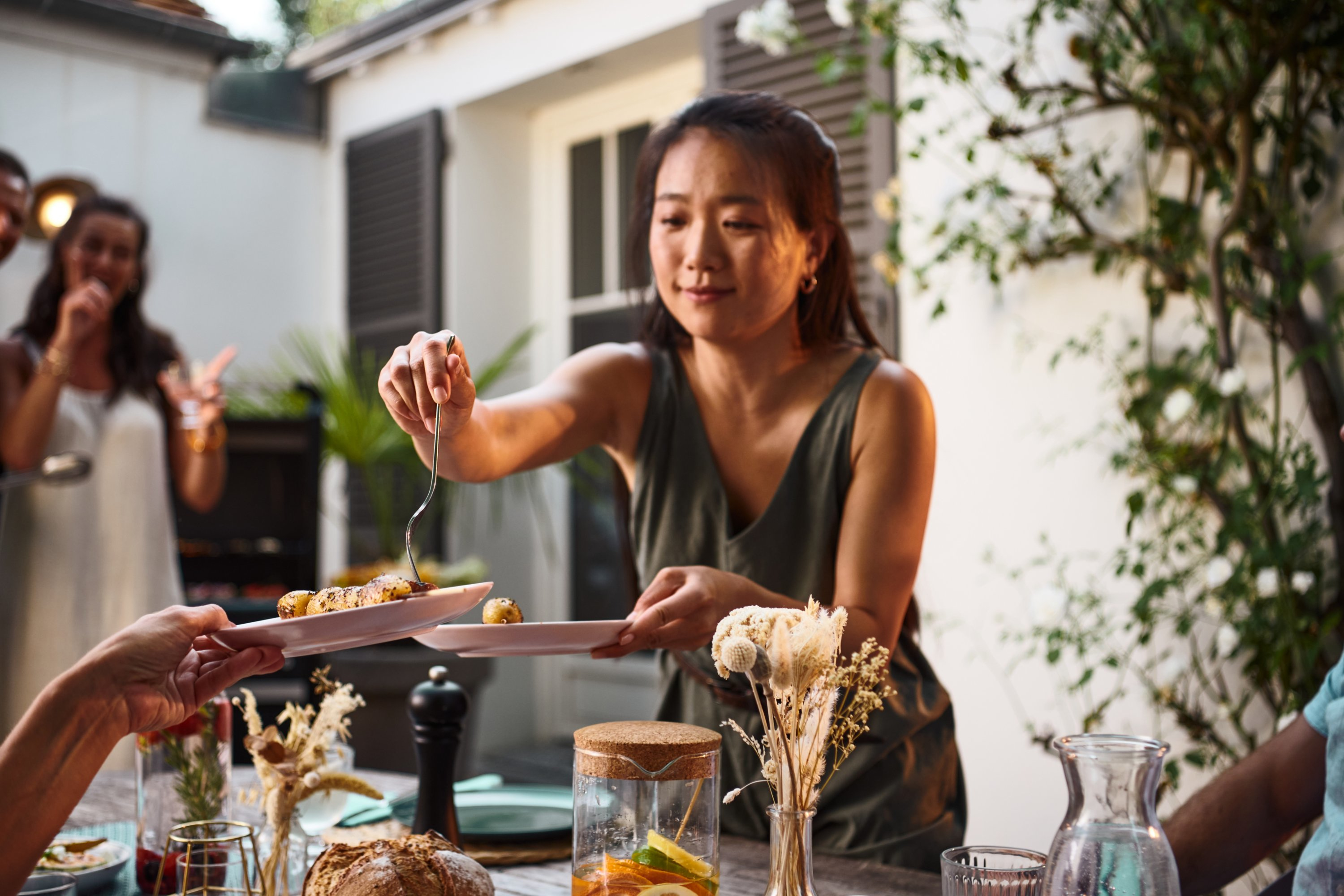 Una donna serve cibo a un raduno all'aperto. Persone sono visibili sullo sfondo.
