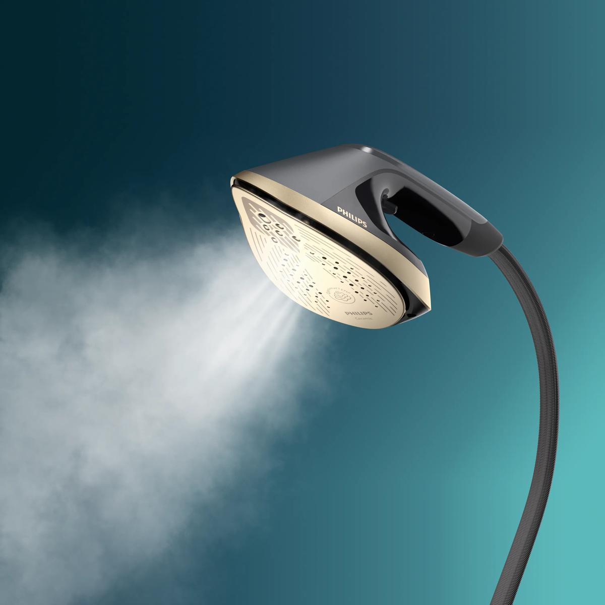 Żelazko Philips ze złotymi akcentami emituje parę na turkusowym tle.
