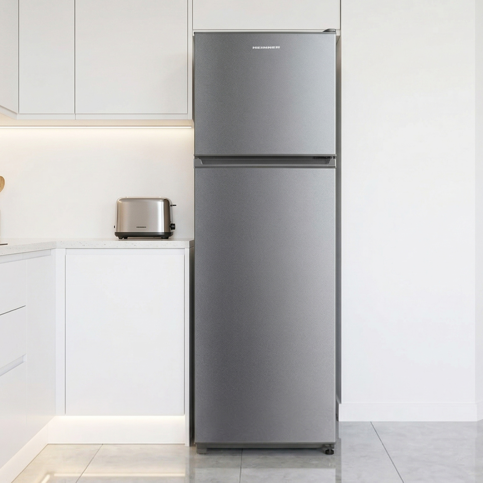 A silver two-door refrigerator stands in a modern kitchen next to a toaster.