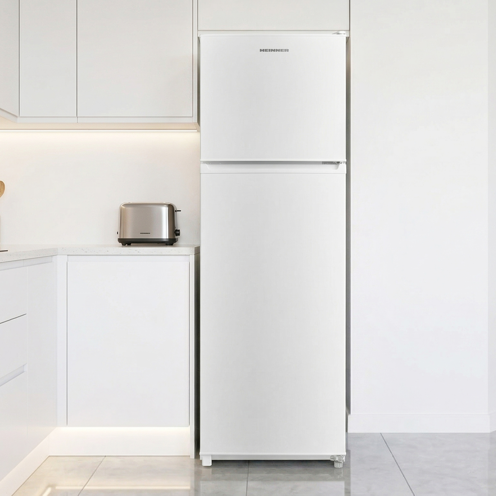Een witte koelkast staat in een moderne keuken naast een zilveren broodrooster.