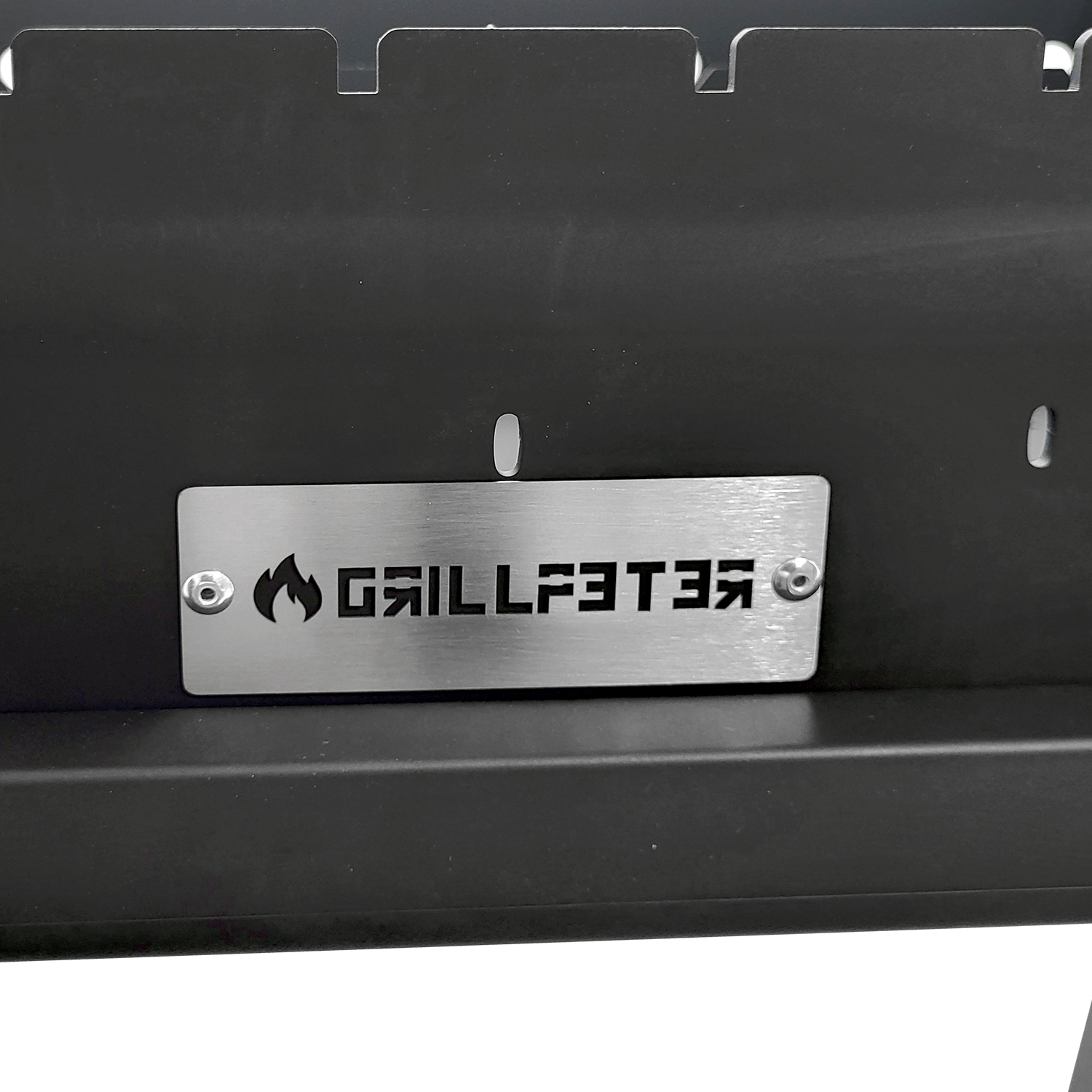 Ein silbernes Schild mit einem Flammenlogo und 'GRILLFEUER' auf schwarzem Grill.