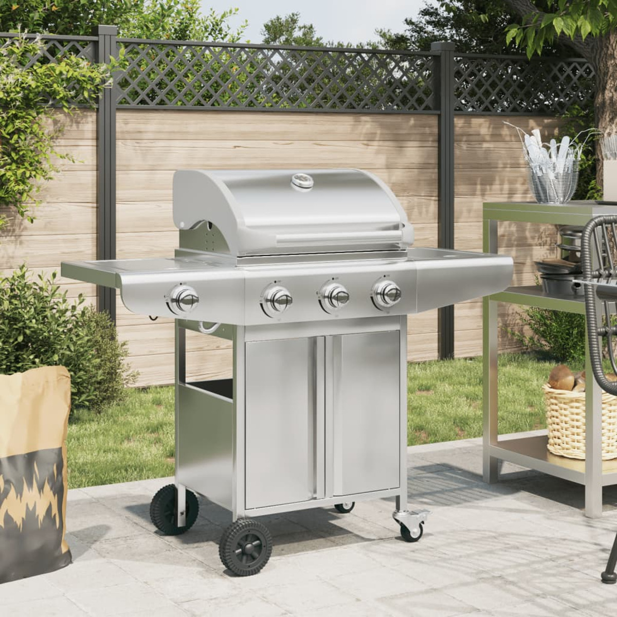 Ein silberner Gasgrill steht auf einer gepflasterten Terrasse neben einem Sack Holzkohle.