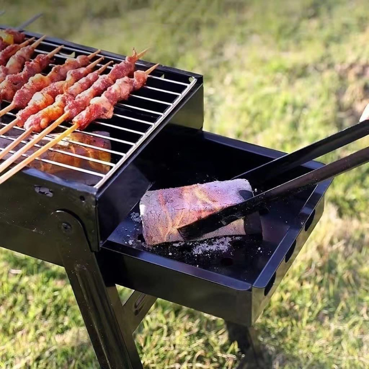 Rohe Fleischspieße auf einem Grill mit glühender Kohle darunter. Zange hält eine große Kohle.