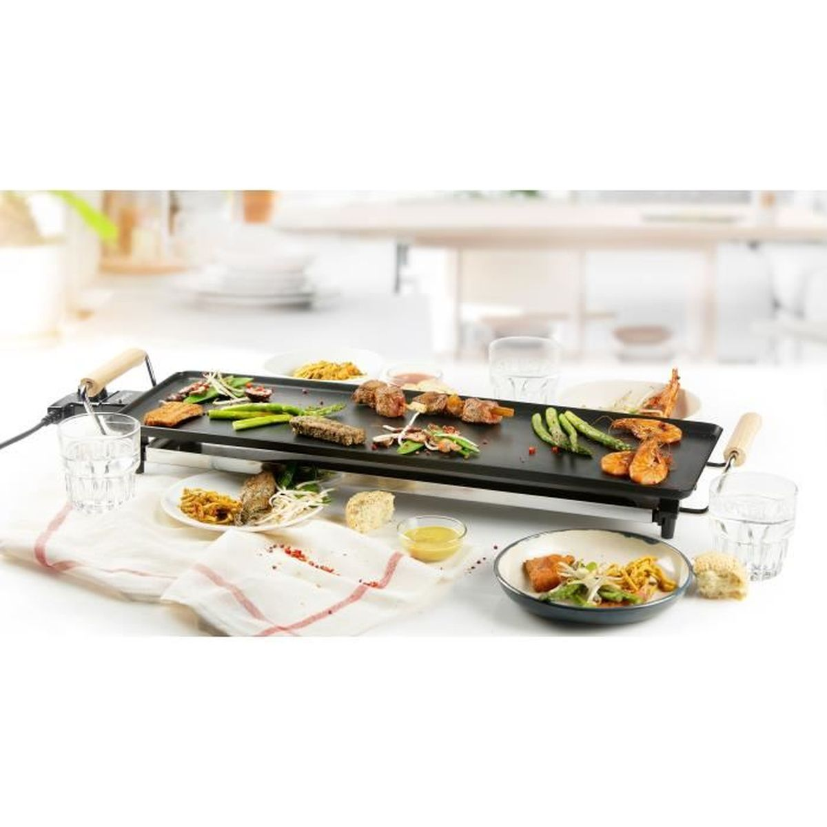 Ein Elektrogrill mit flacher Platte und Speisen: Spieße, Garnelen, Spargel und Steak.