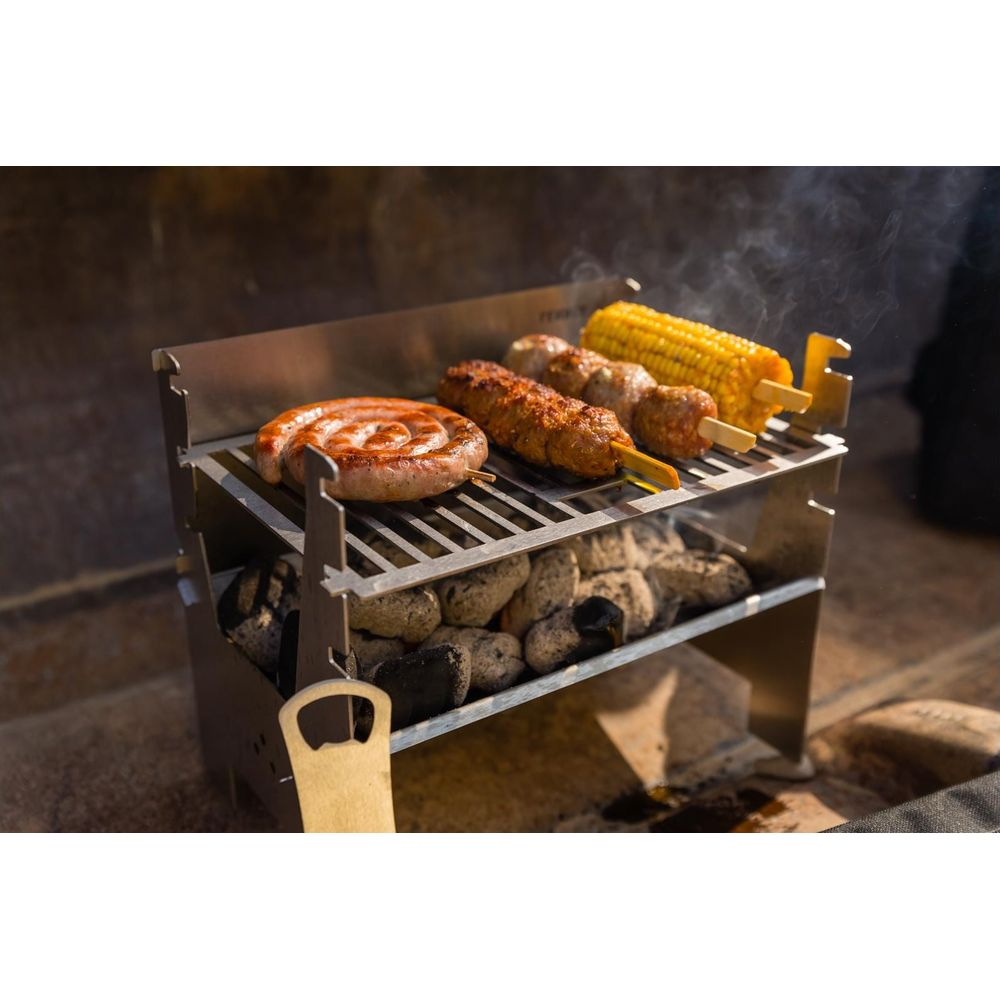 Eine Grillwurst und Spieße auf einem Metallgrill über glühenden Kohlen.