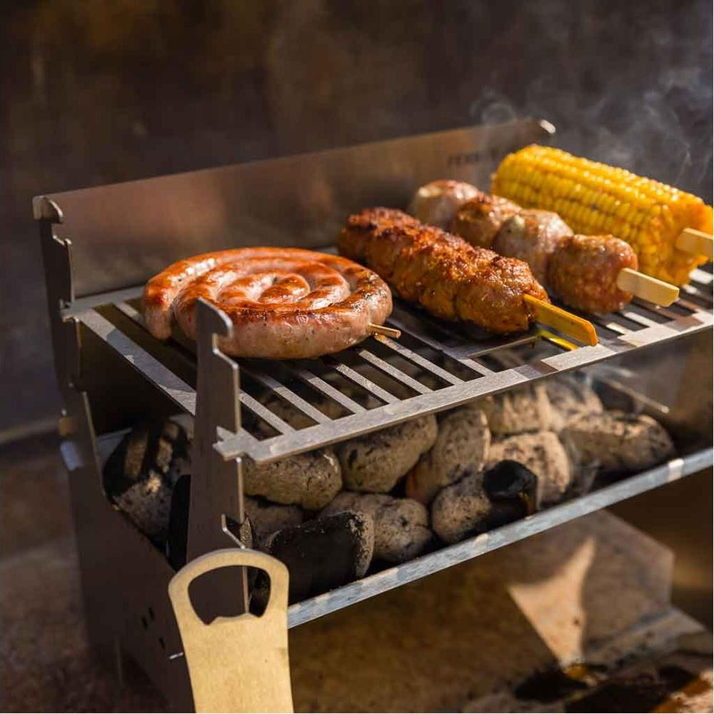 Eine gewickelte Wurst, Kebabs und Maiskolben garen über Holzkohle auf einem Metallgrill.