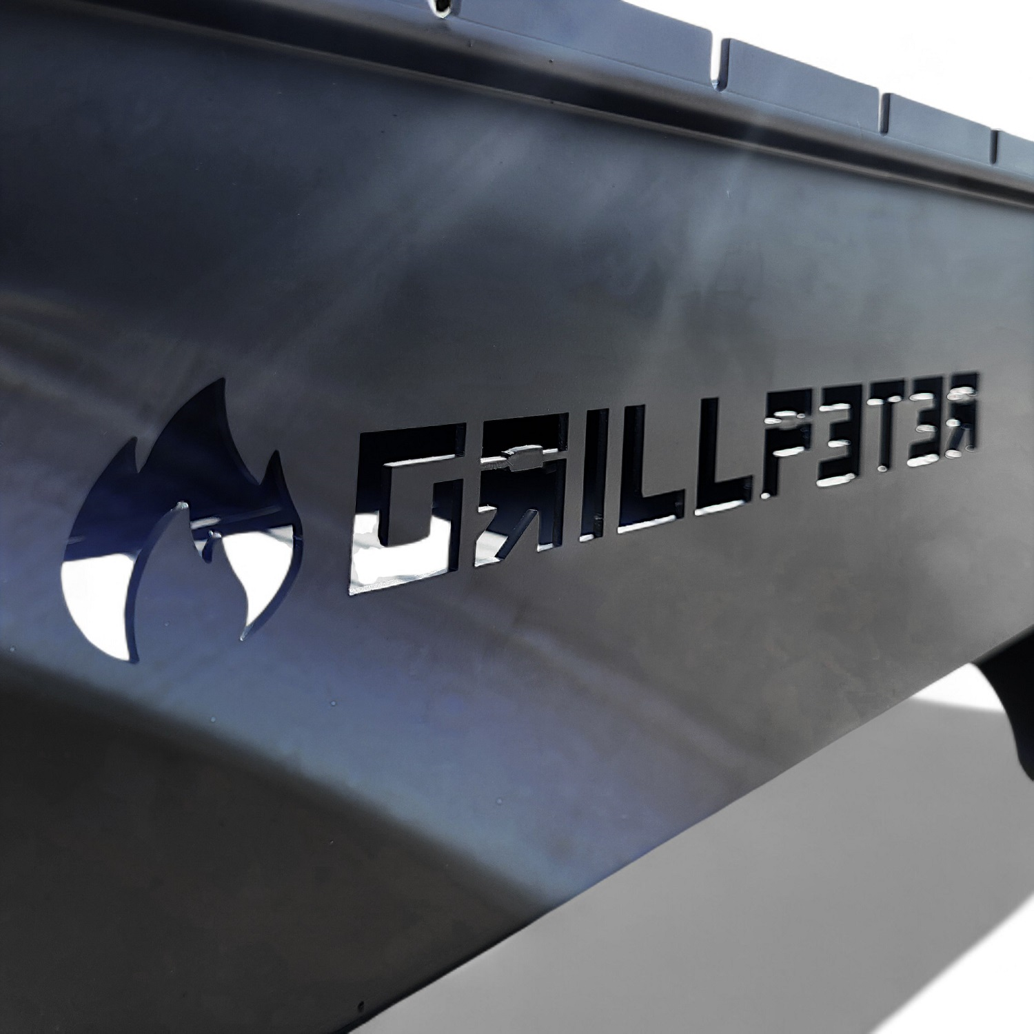 Ein schwarzer Grill mit dem Markennamen GRILLFESTER, der in den Metall geschnitten ist.