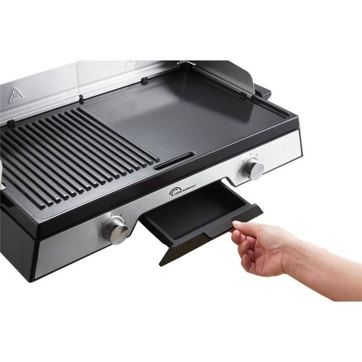 Eine Hand zieht eine Fettauffangschale unter einem Grill mit gerippter und flacher Oberfläche heraus.