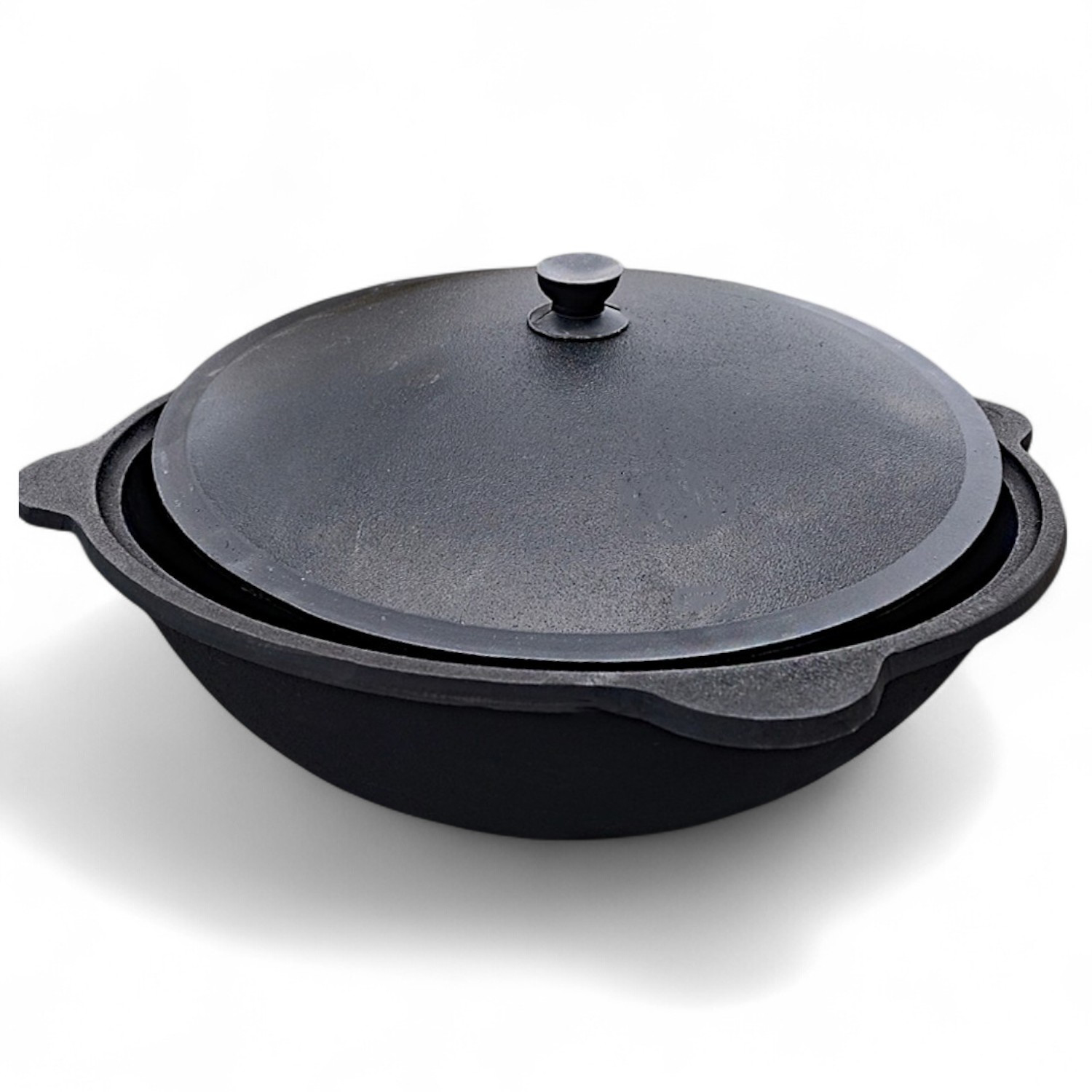 Eine schwarze Gusseisenpfanne mit Deckel, auf weißem Hintergrund.