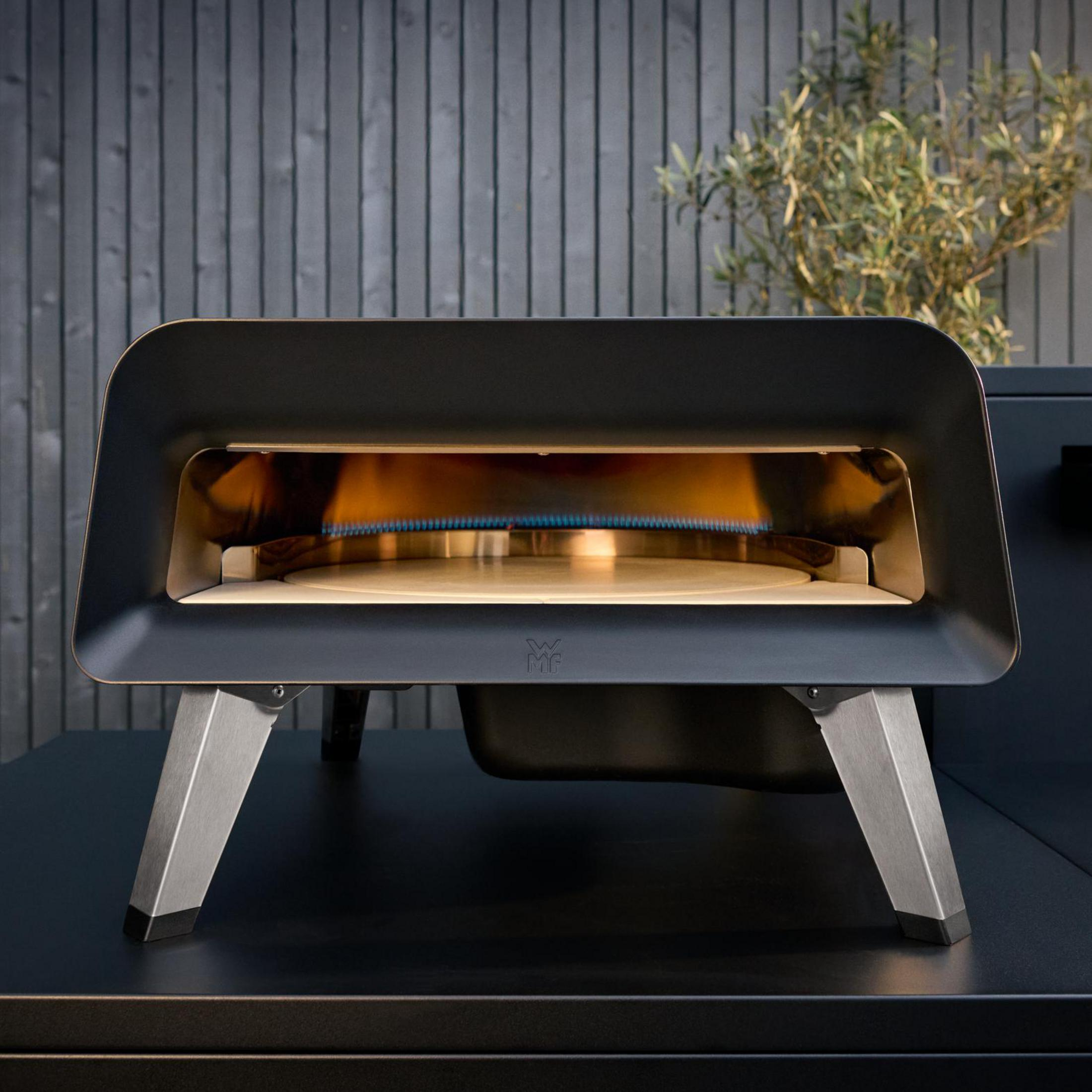 Forno per pizza nero con fiamme e pietra refrattaria. Gambe metalliche su superficie nera.