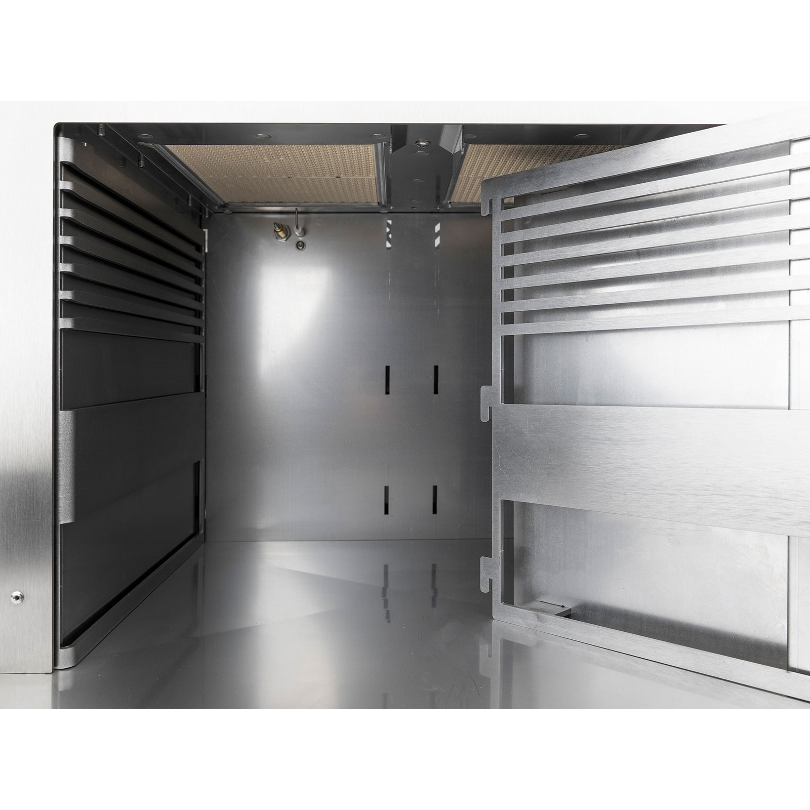 Innenansicht eines Metallgeräts mit Lüftungsschlitzen und geöffneter Tür.