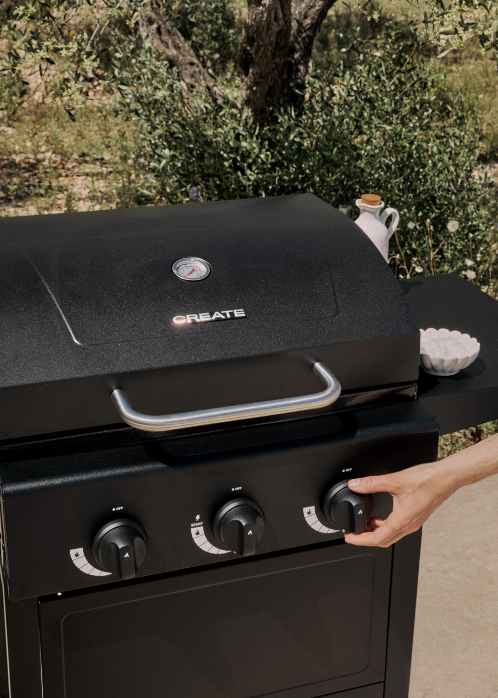 Parrilla negra con asa de acero inoxidable, mano gira mando. Exterior.