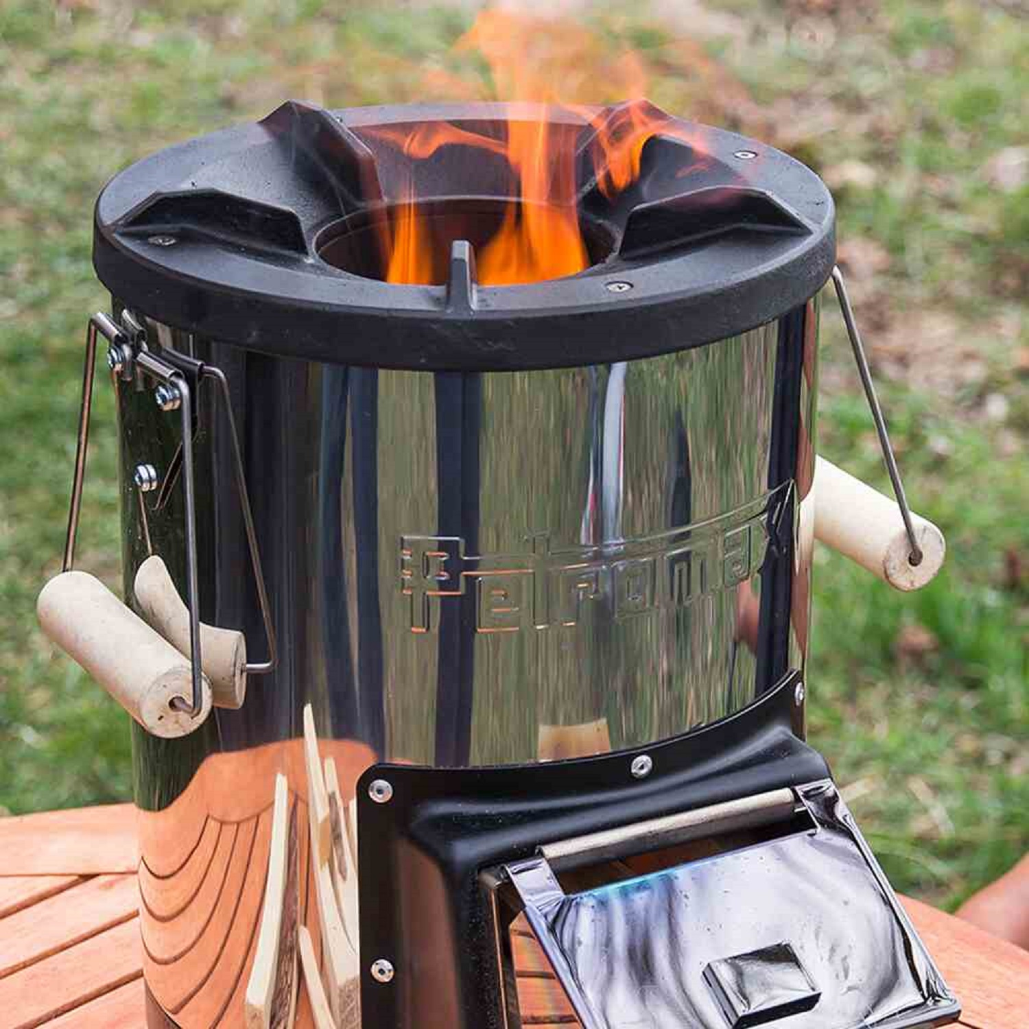 Ein glänzender Metallofen mit Flammen, der auf einem Holztisch steht.