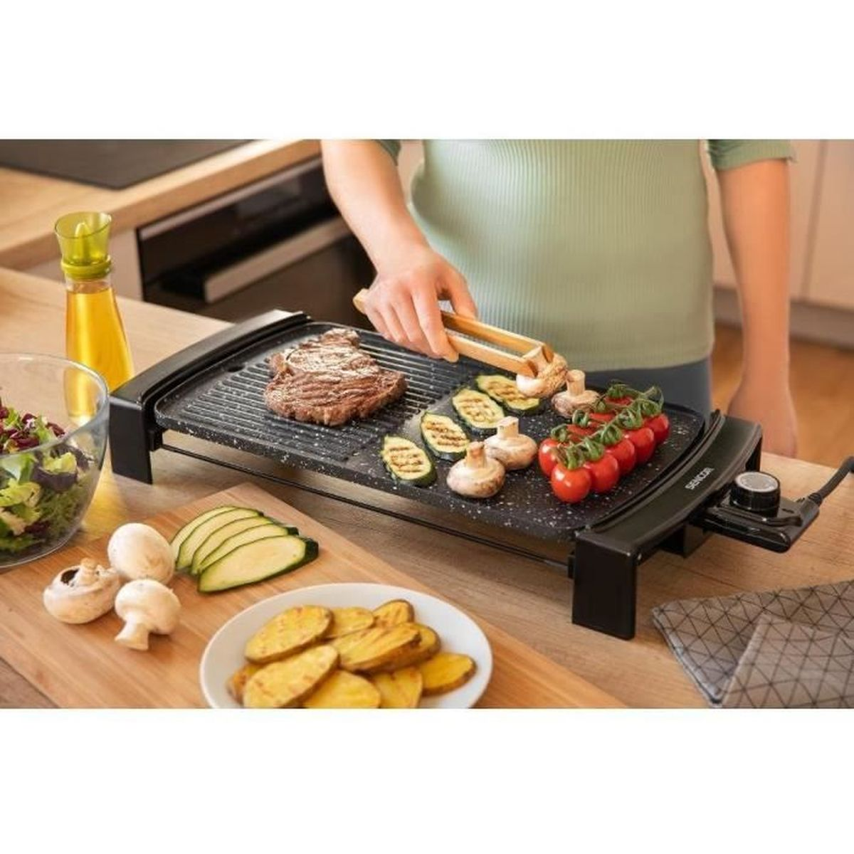 Una persona griglia bistecca, zucchine, funghi e pomodori su una piastra elettrica.