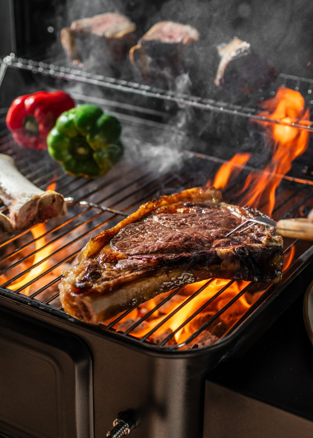 Bistec a la parrilla con pimientos y humo. Llamas visibles.